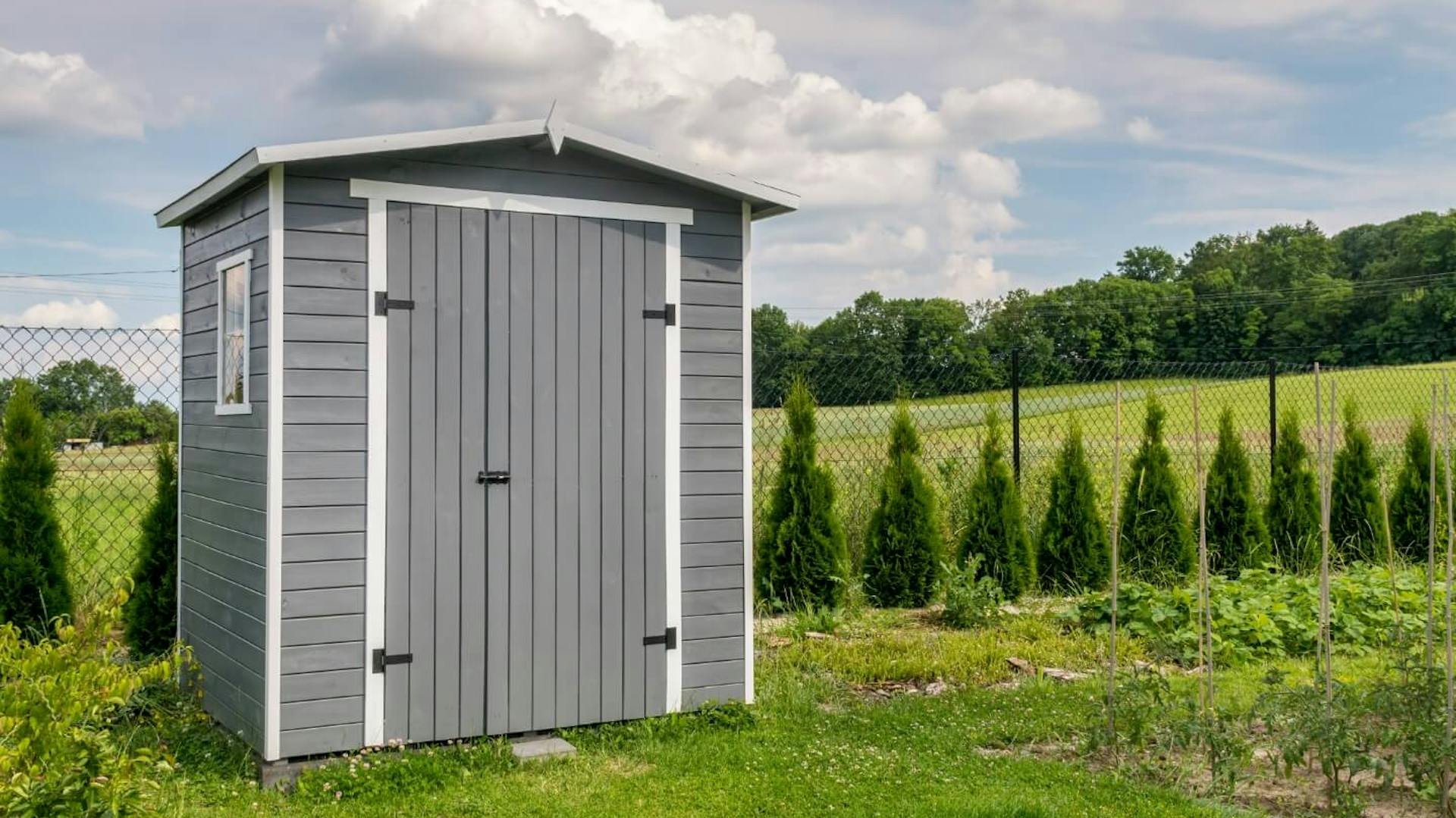 Kleiner grauer Geräteschuppen im Garten.