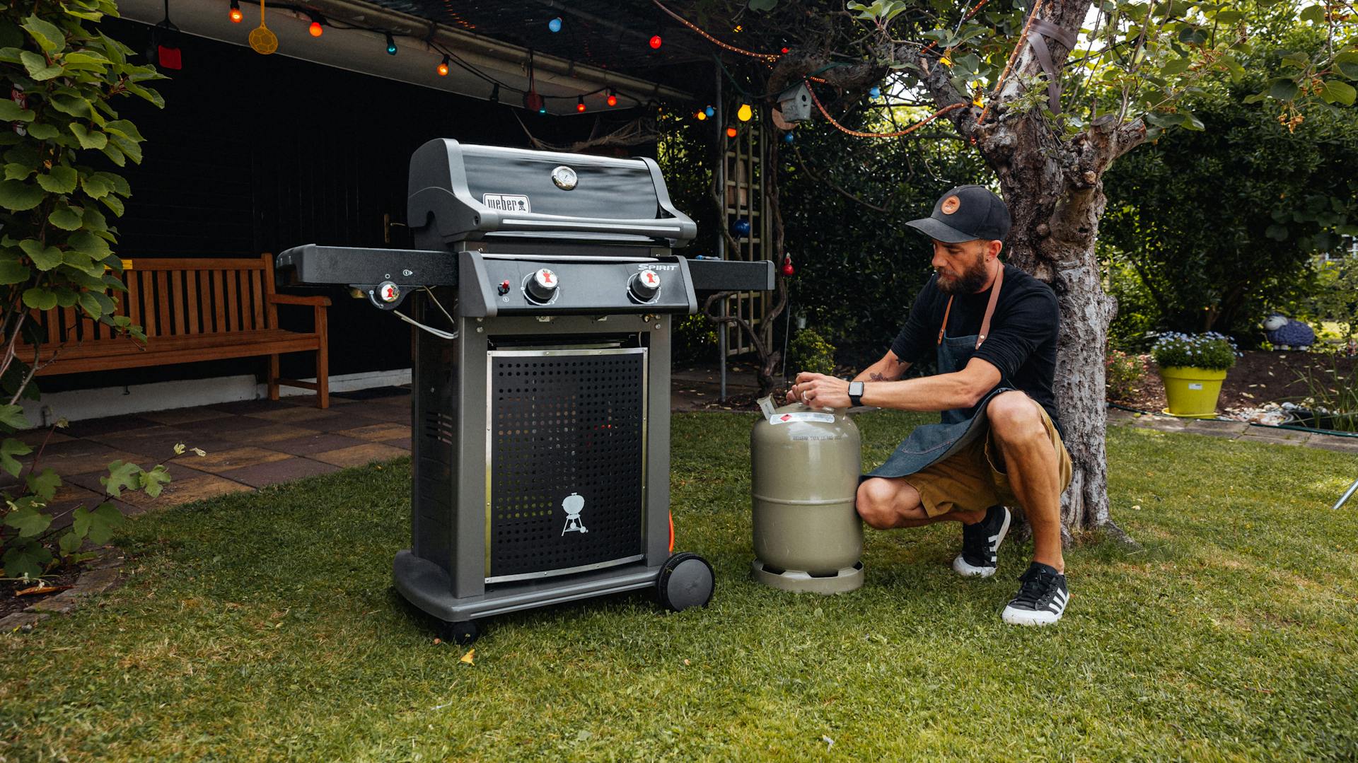 Mann lagert Gasflasche neben seinem Gasgrill