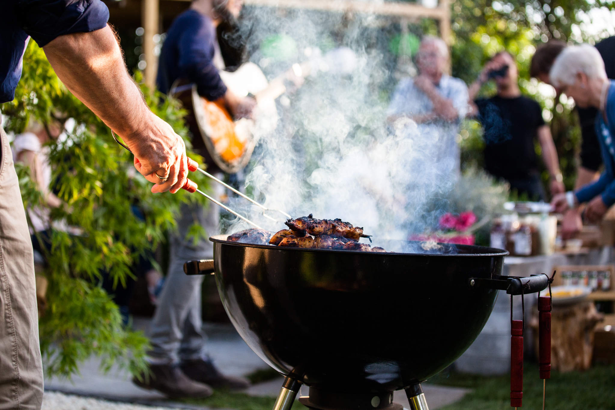 Ein Man grillt am Grill für die Familie.