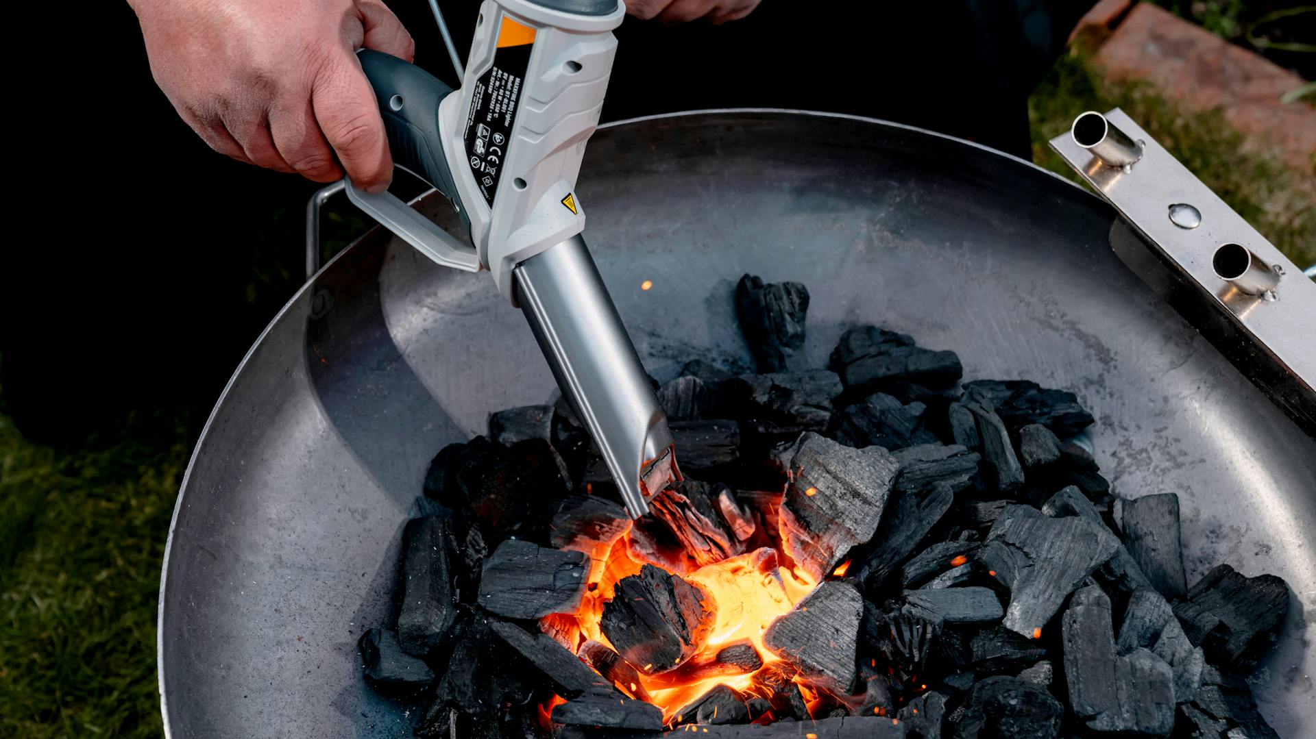 Valaki egy akkus grillgyújtót tart faszén fölött