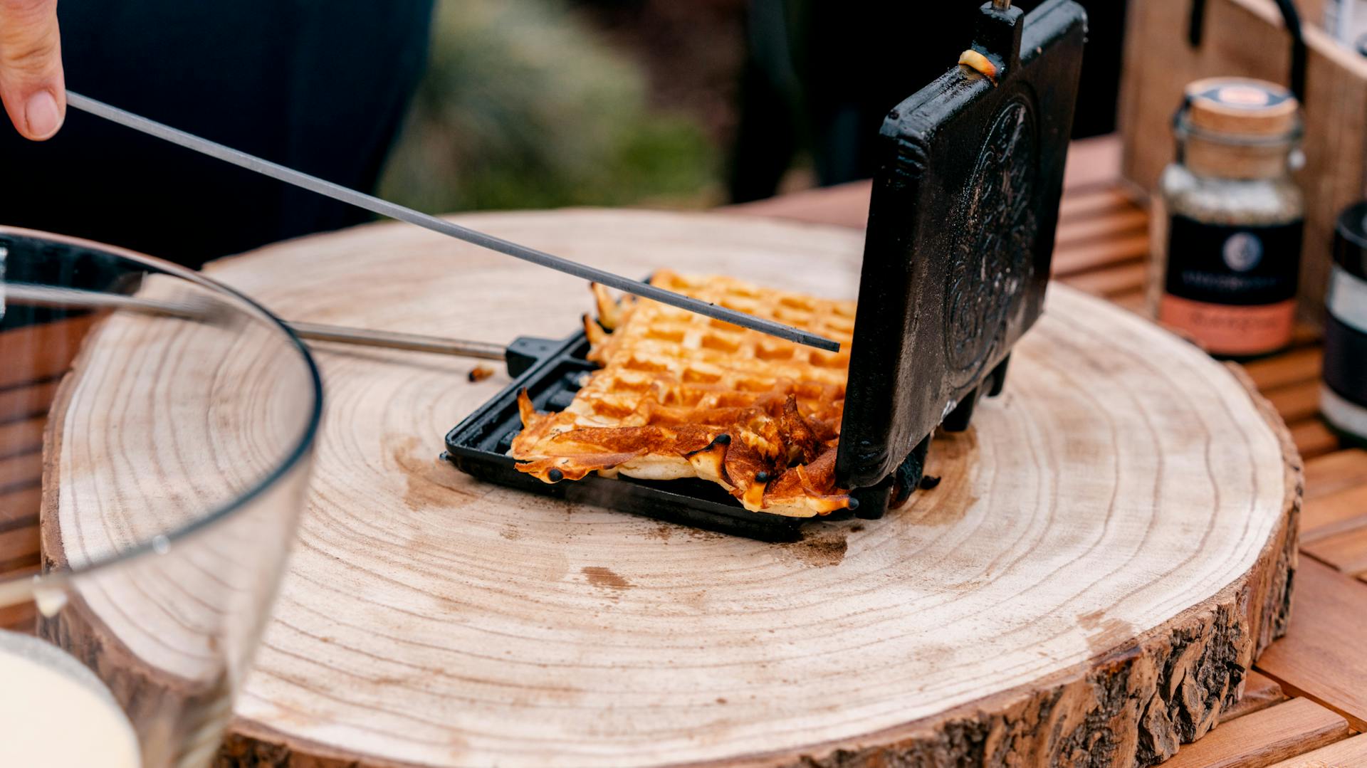 Egy ember egy grilleszközökkel megrakott asztal mögött áll.