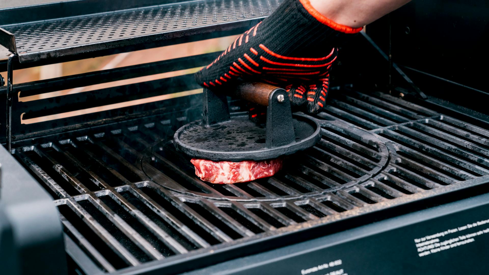 Egy kéz húsnehezéket nyom egy húsdarabra