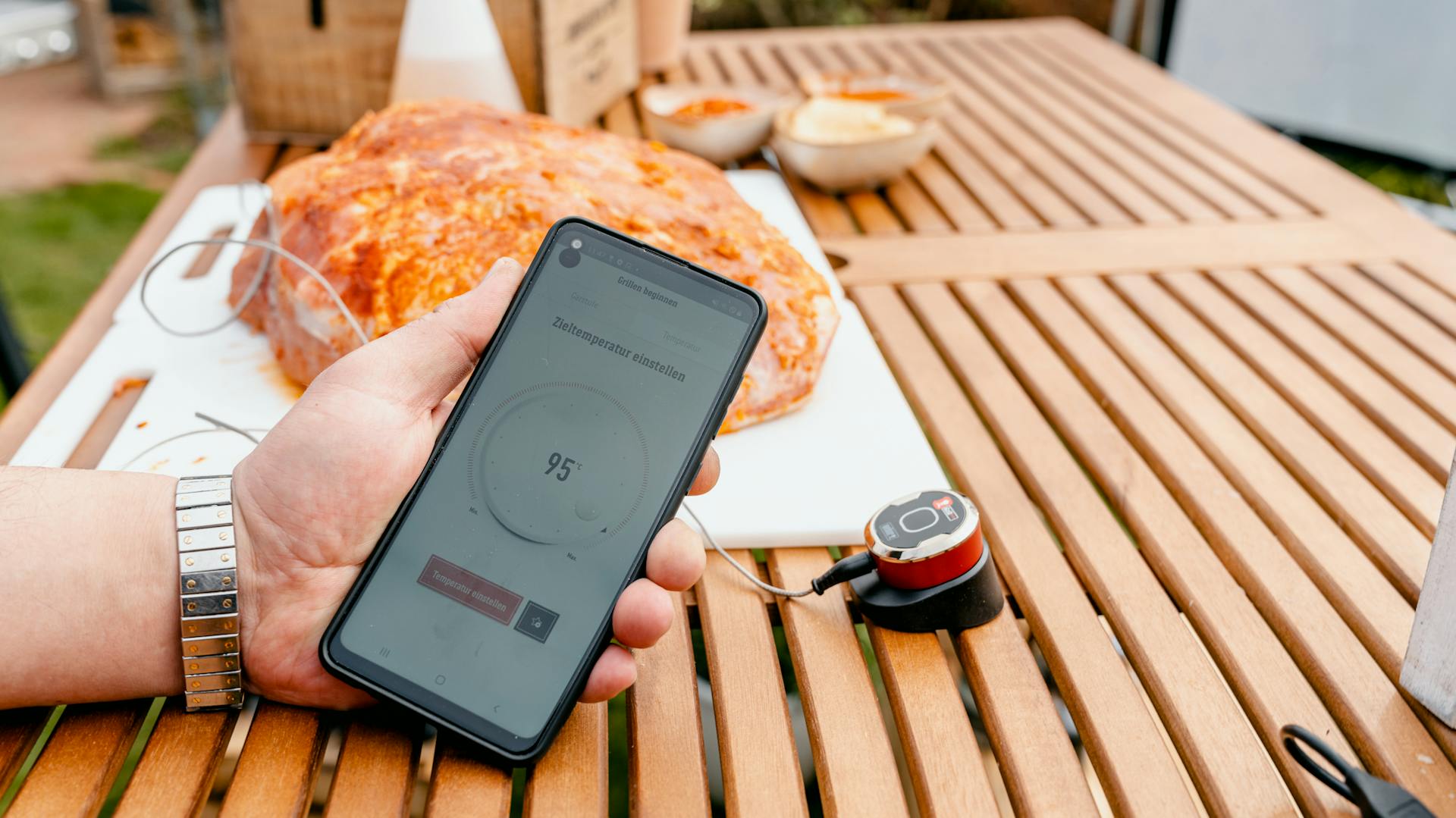 Egy kézben tartott mobiltelefon egy darab hús előtt