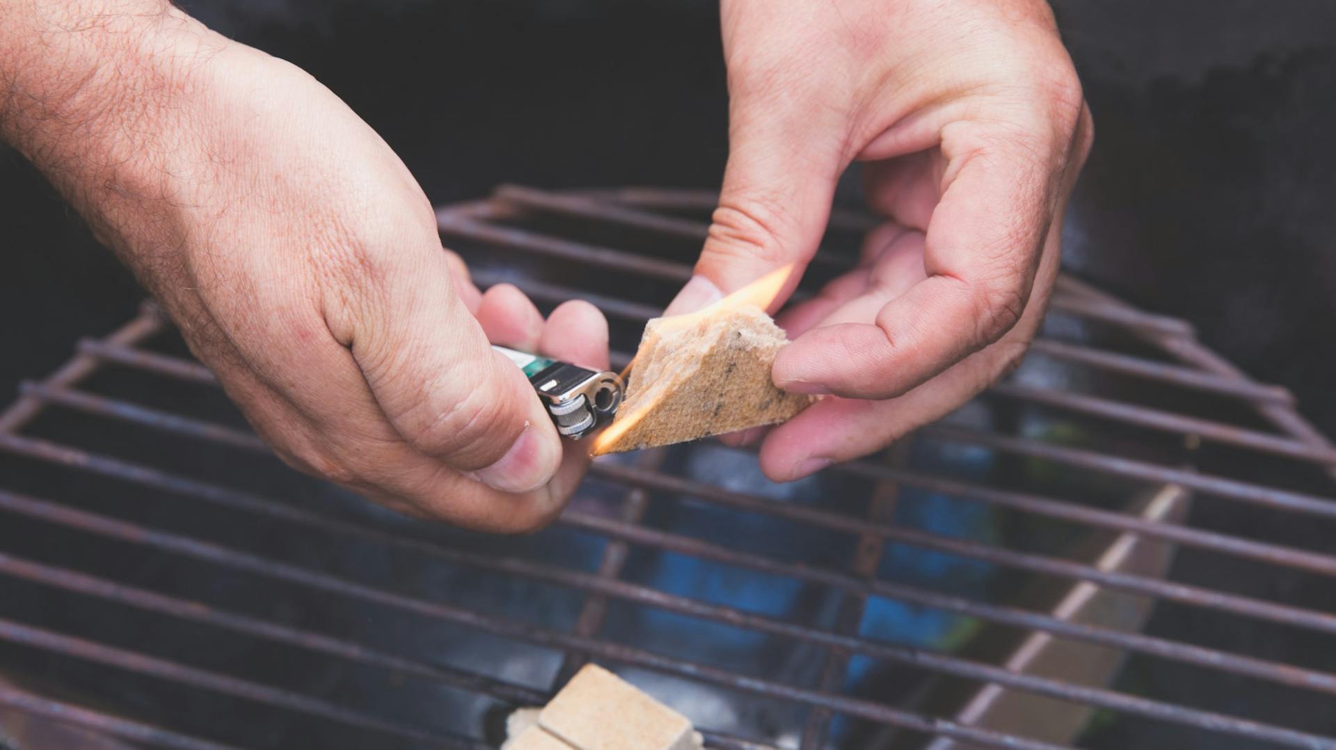 Mann zündet Grillanzünder mit Feuerzeug an
