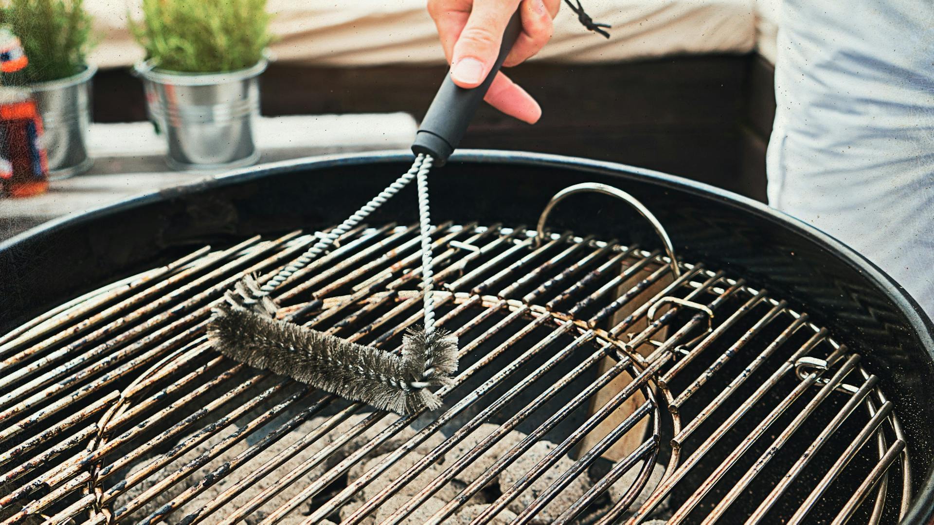 Drótkefével tisztítják a faszenes grillsütőt.
