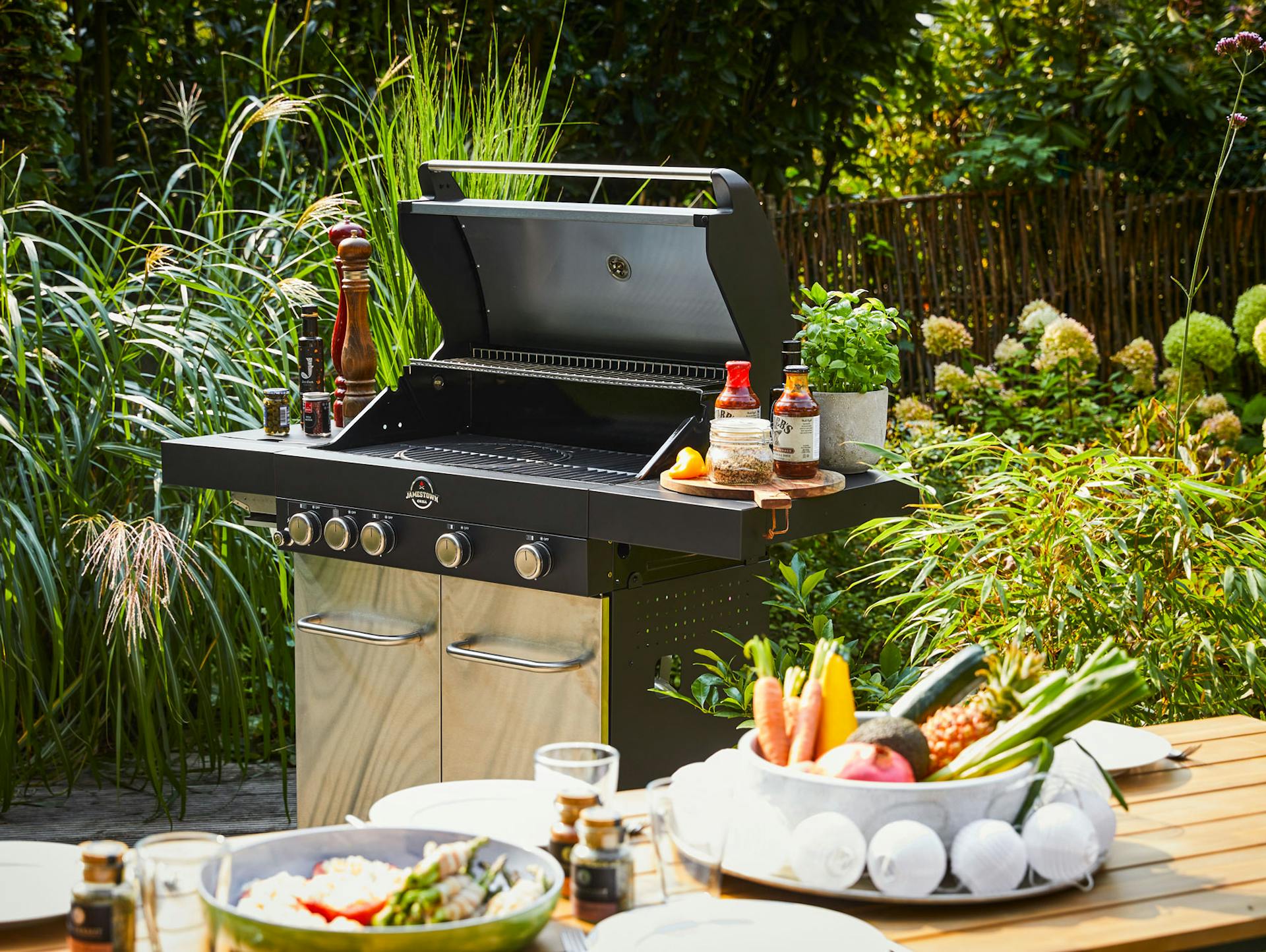 Gasgrill mit vorbereiteten Speisen im Vordergrund