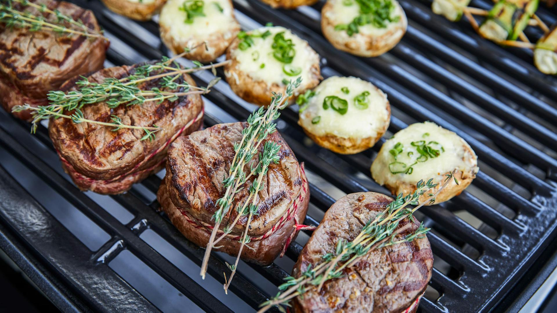 Steaks mit Kräutern neben gefüllten Champignons