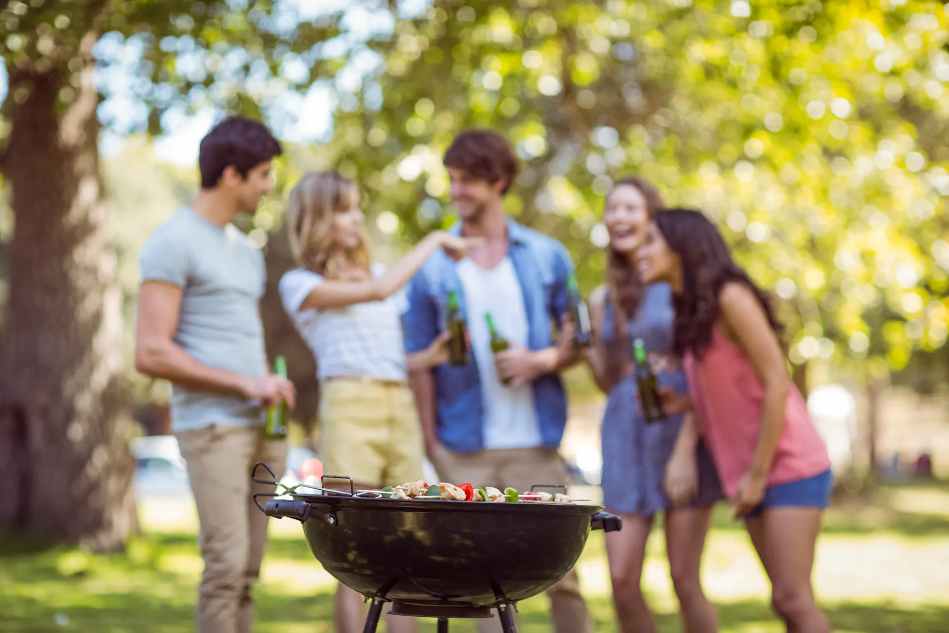 Eine Personengruppe im Hintergrund eines brennenden Kugelgrills