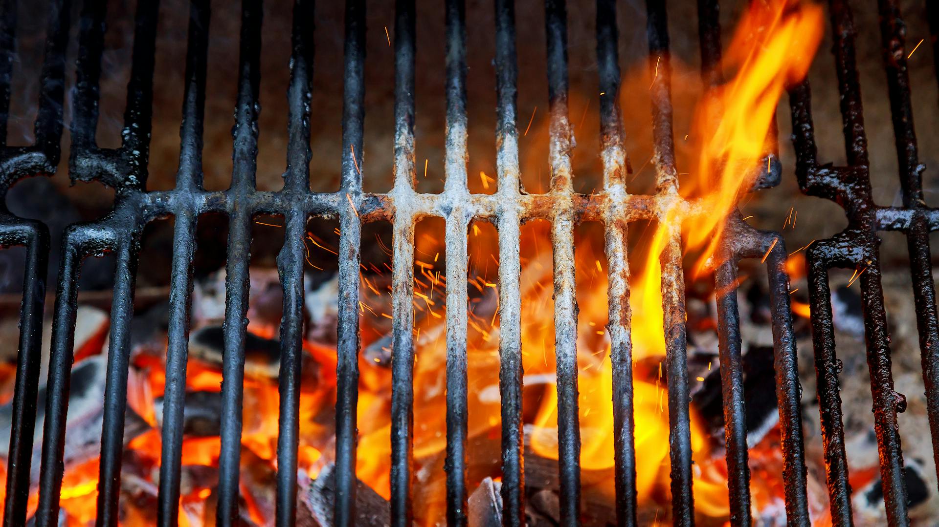 Plamene obklopujú grilovací rošt.