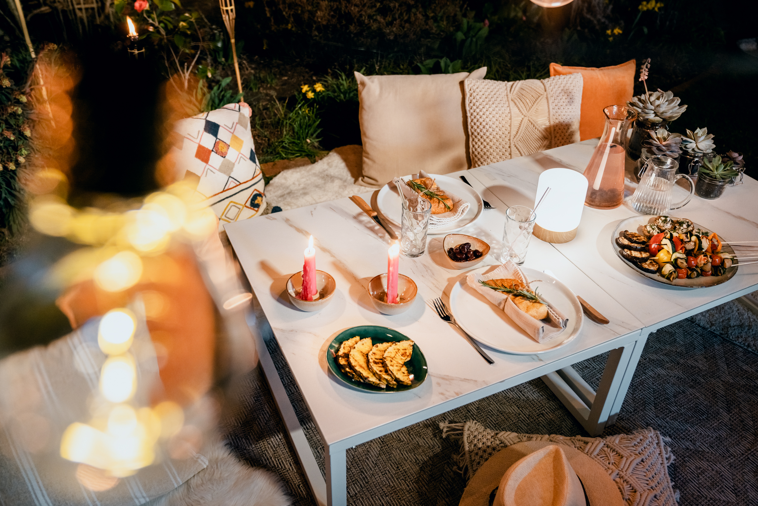 Gedeckter Gartentisch draußen bei Nacht mit gemütlicher Gartenbeleuchtung