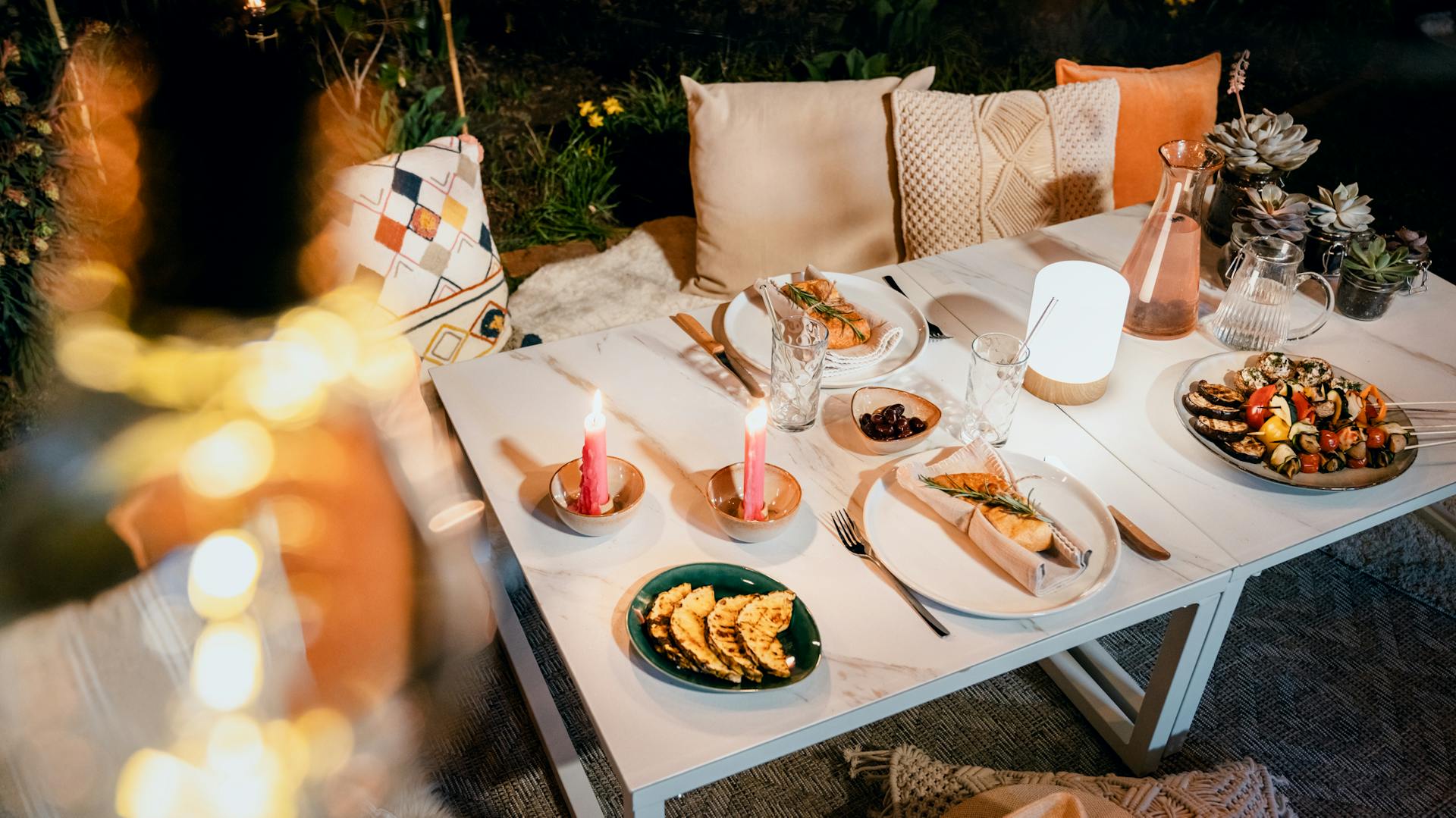 Gedeckter Gartentisch draußen bei Nacht mit gemütlicher Gartenbeleuchtung