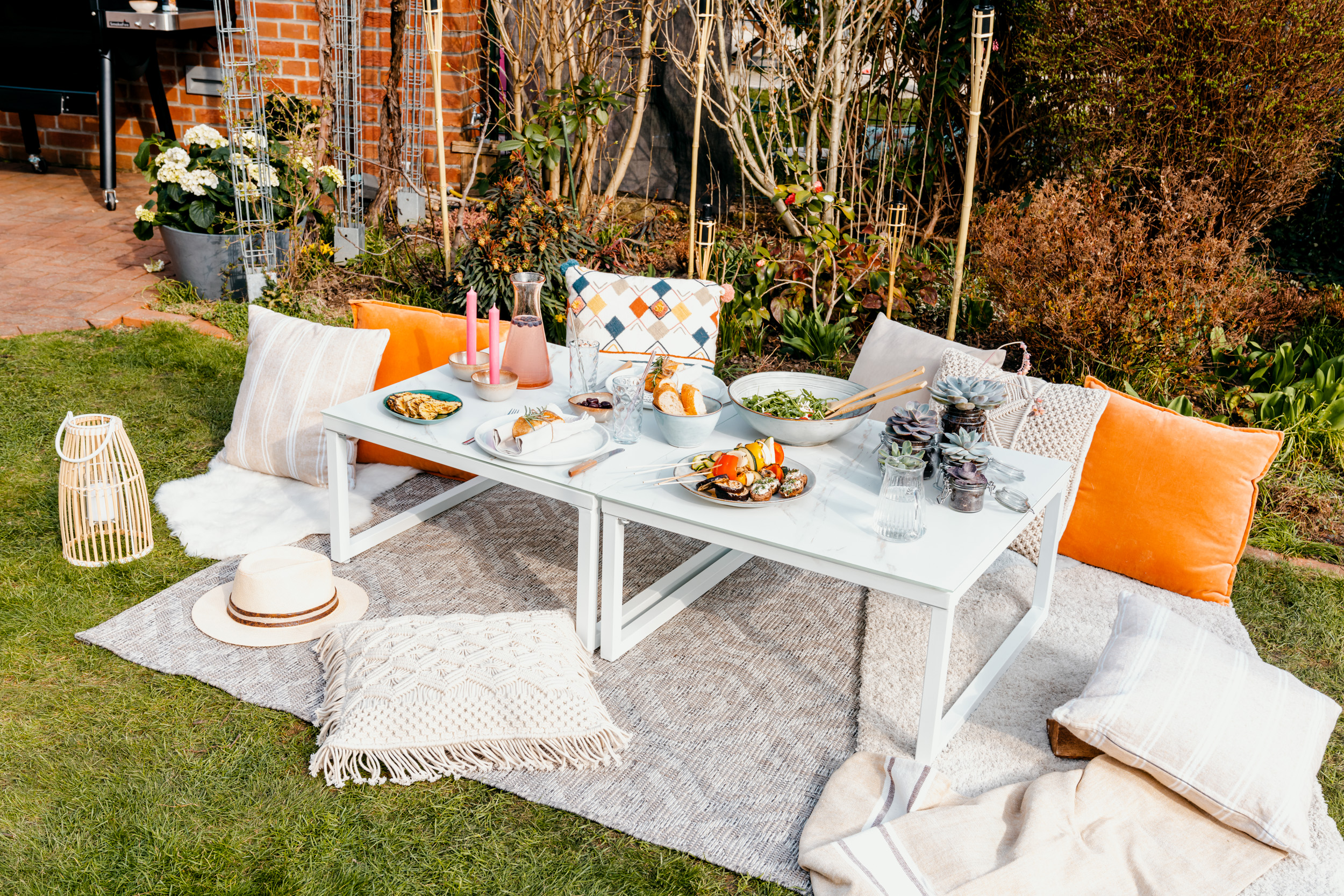 Posto a sedere in giardino con tavolo celeste apparecchiato e cuscini