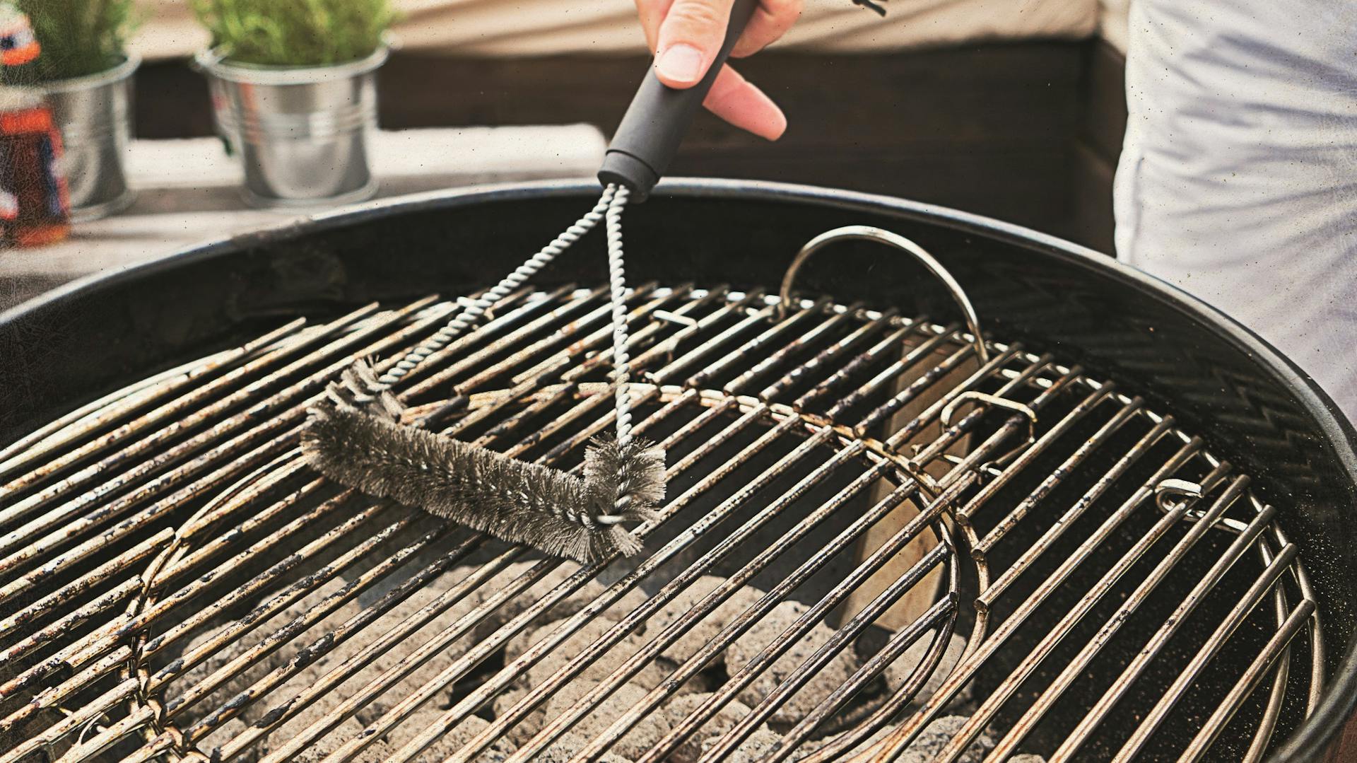 Una persona pulisce la griglia di un grill a carbone