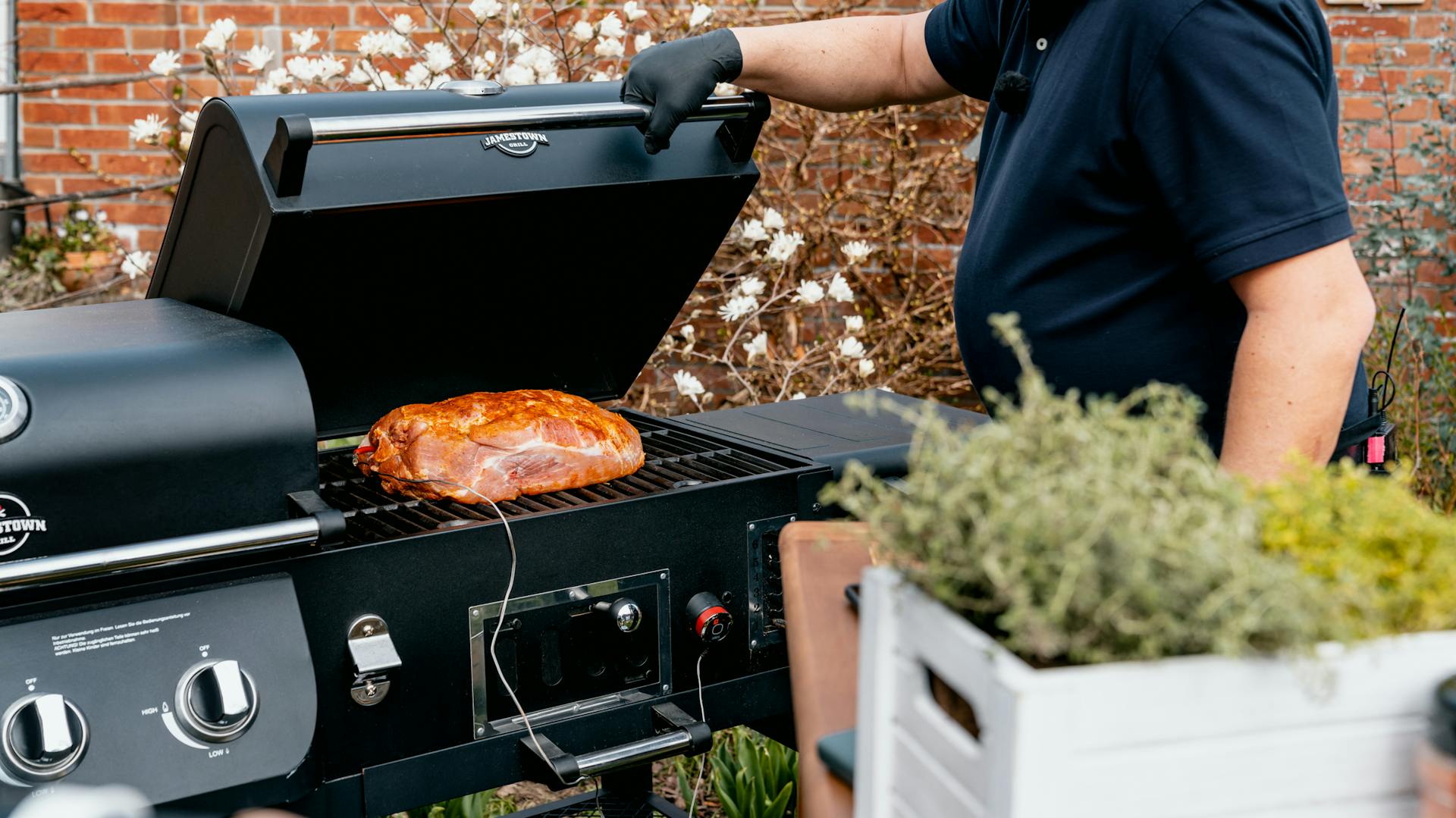 Mann steht am Grill und überprüft Grillgut