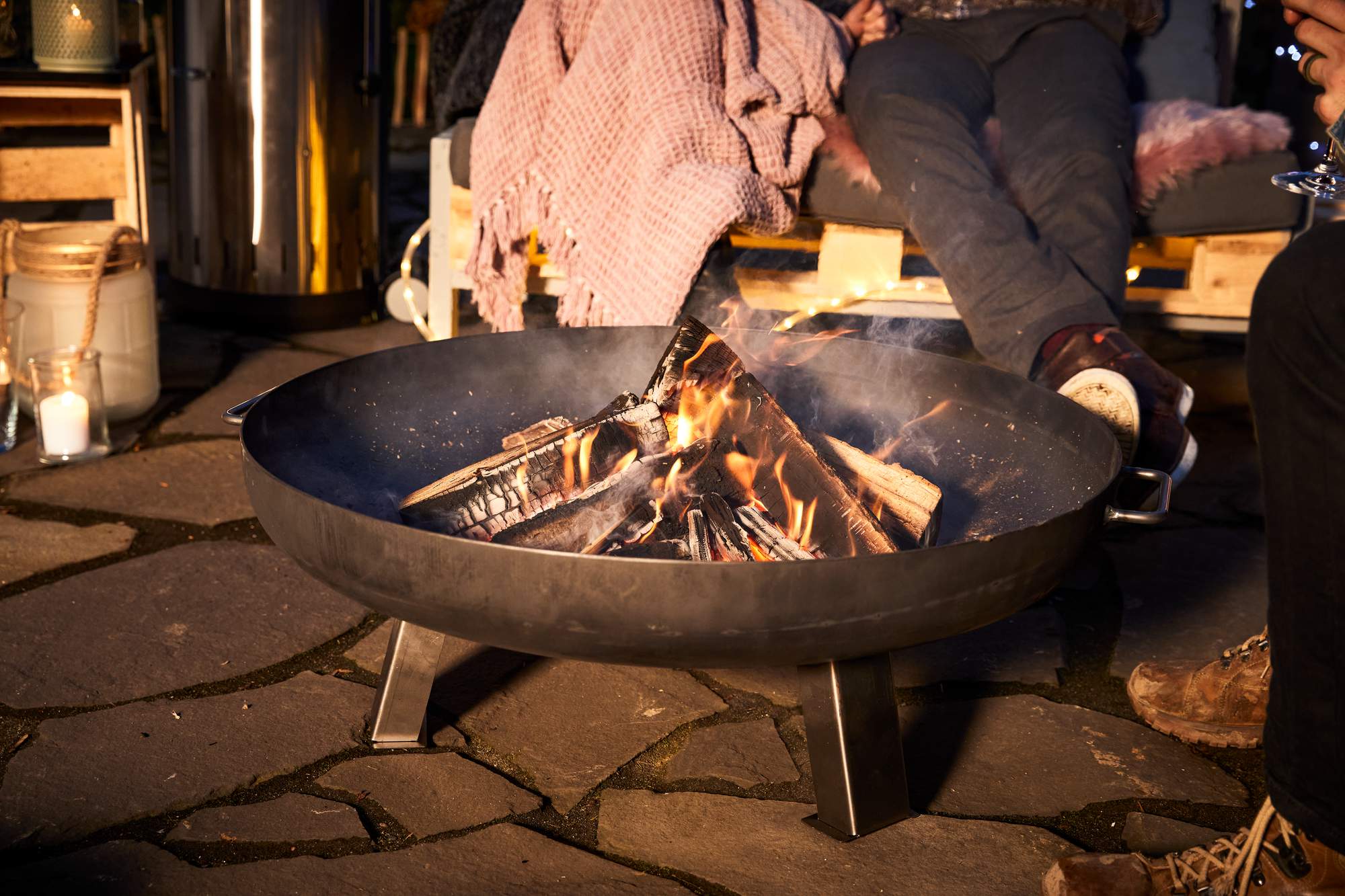 Alcune persone sedute alla sera con coperte intorno al braciere.