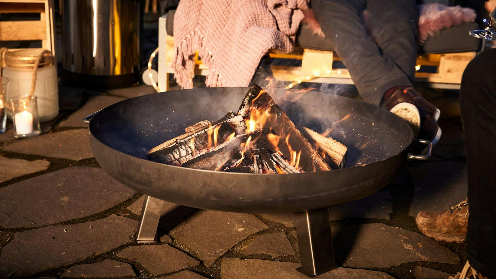 Alcune persone sedute alla sera con coperte intorno al braciere.