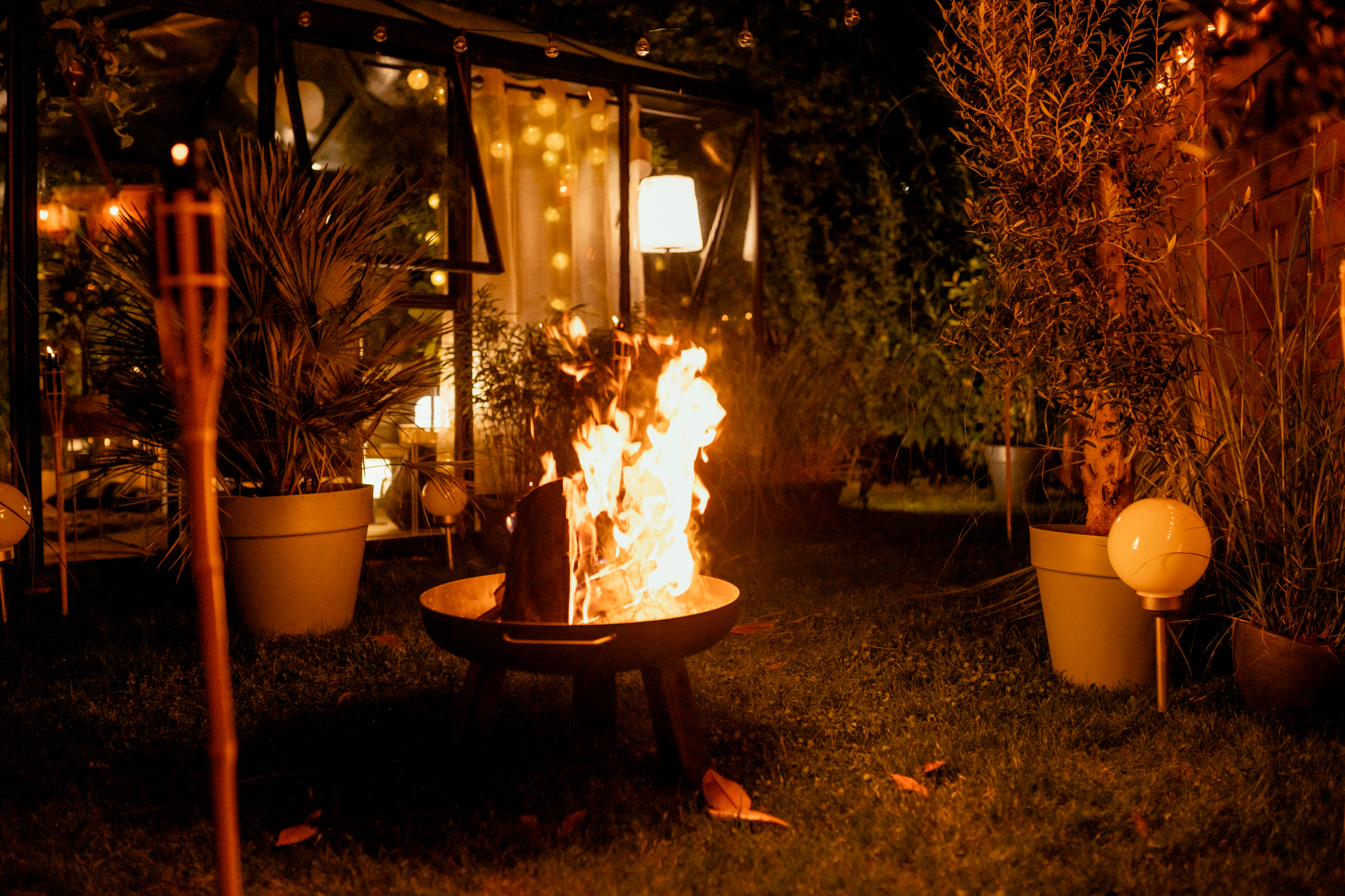 Feuerschale im Garten neben beleuchtetem Gartenhaus
