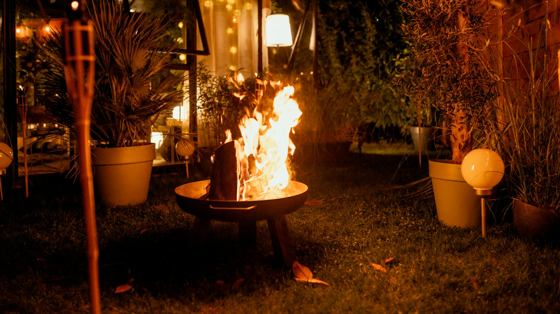 Feuerschale im Garten neben beleuchtetem Gartenhaus