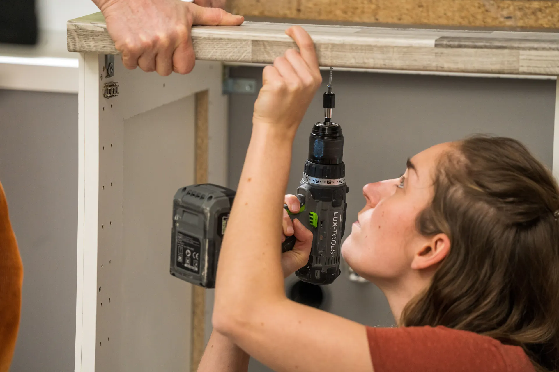 A barkácsolók felcsavarozzák a konyhai munkalapot az alsó szekrényekre.