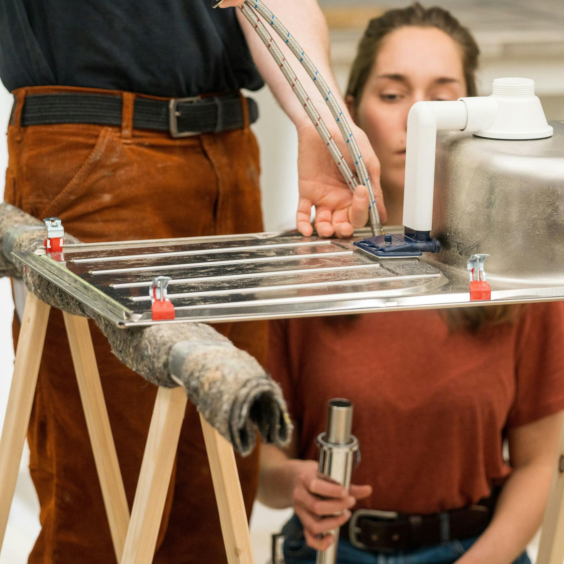 Domáci majster vzájomne skrutkuje drez a armatúru.