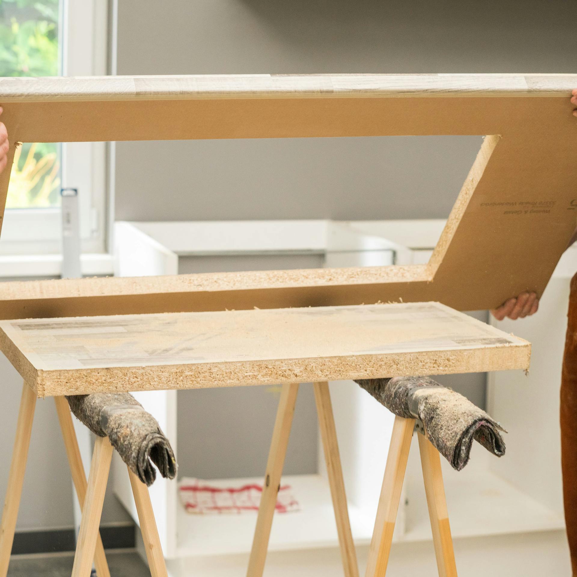 Domáci majstri zdvíhajú pracovnú dosku s výrezom určeným pre drez.