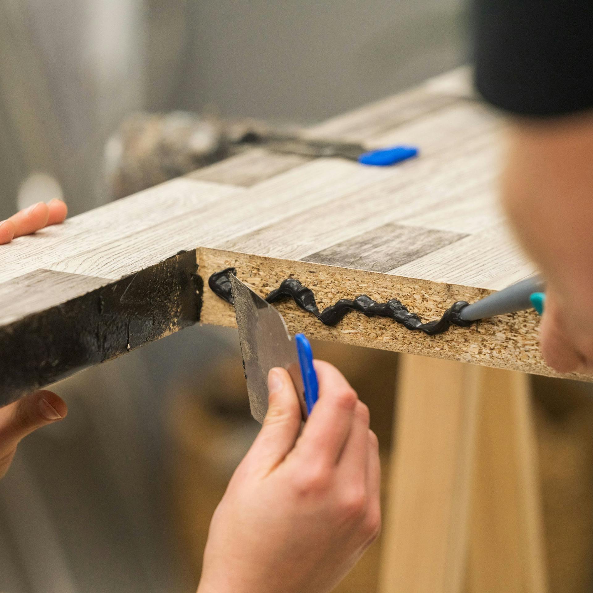 Domáci majster pečatí reznú hranu silikónom a stierkou.