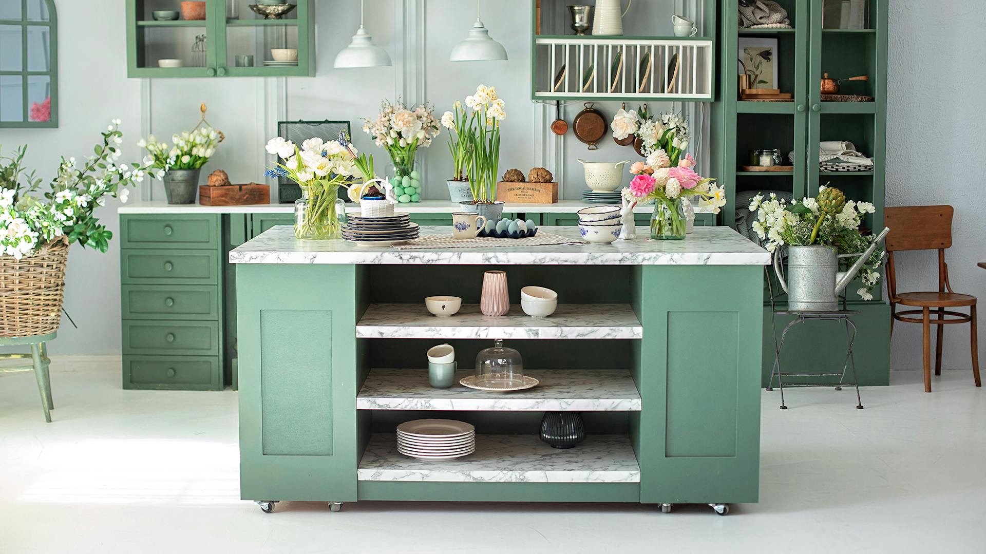 Zöld konyhabútor világos márvány konyhai munkalappal, sok virággal.