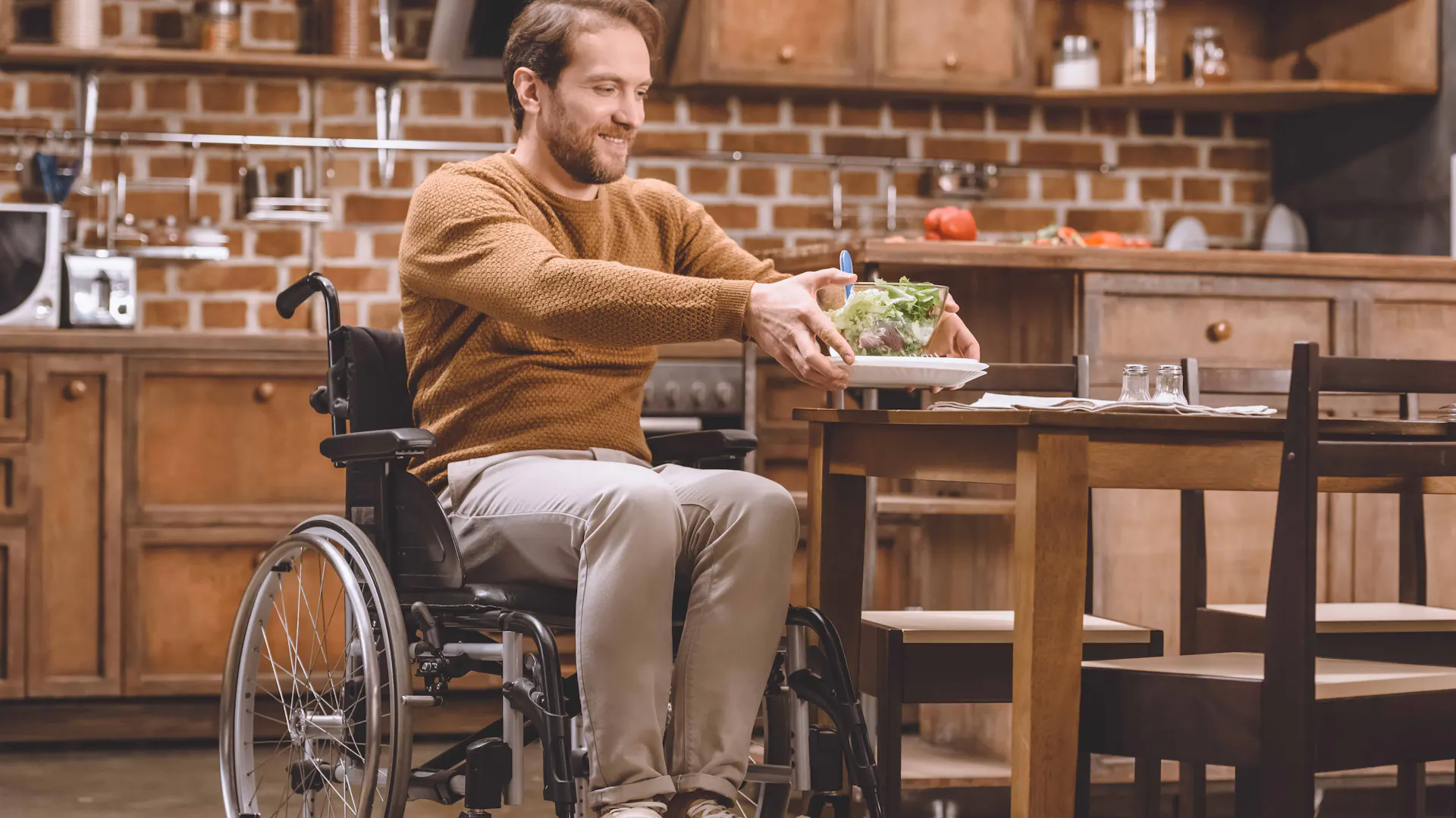 Mann im Rollstuhl stellt eine Schüssel auf einen Tisch