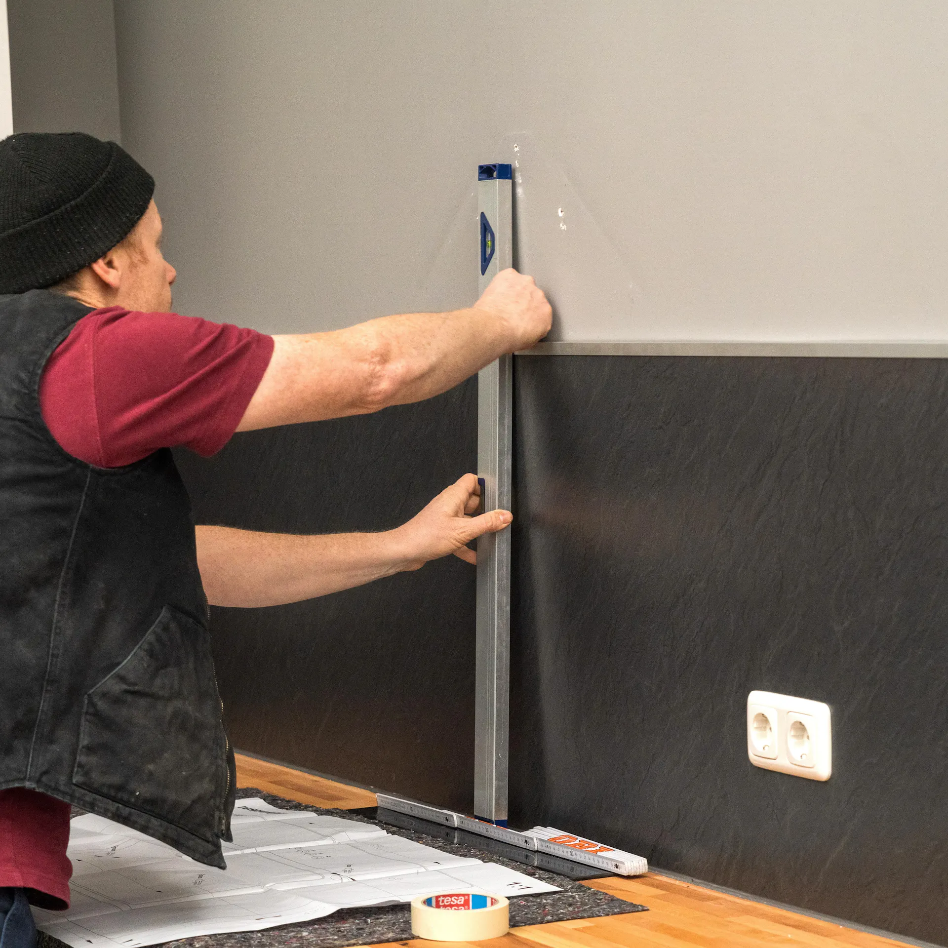 Heimwerker messen die Wand für die Montage einer Dunstabzugshaube ab.