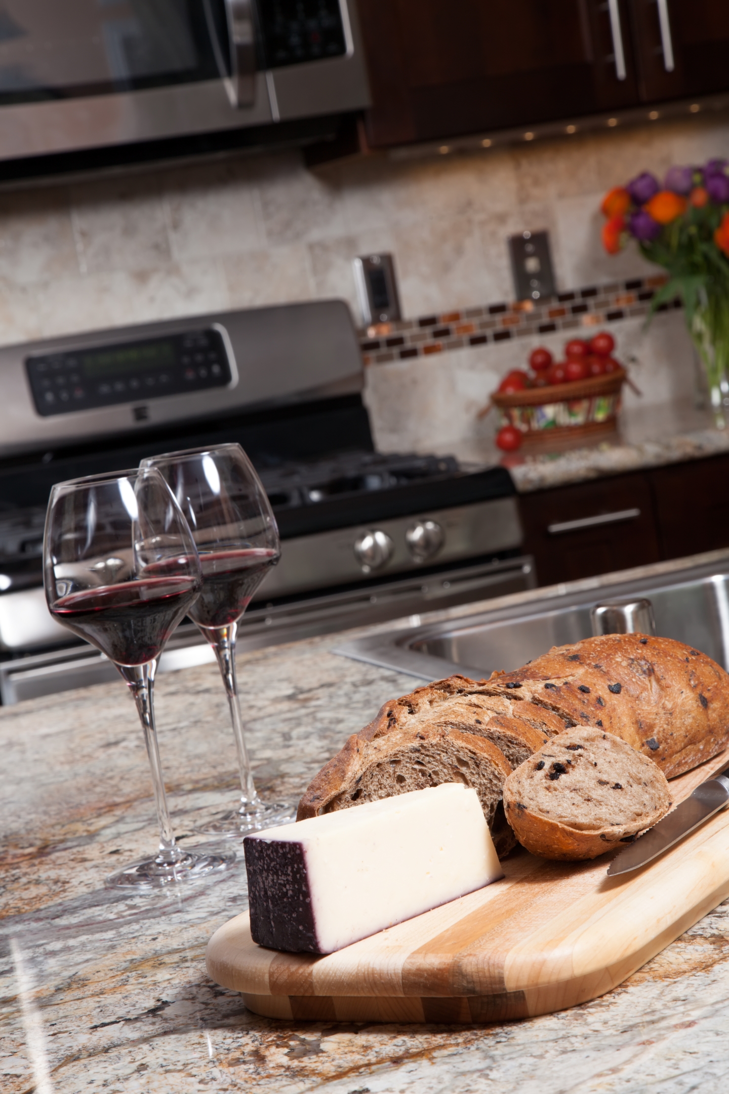 Zwei Gläser Wein, Käse und Brot stehen auf Granitarbeitsplatte. 