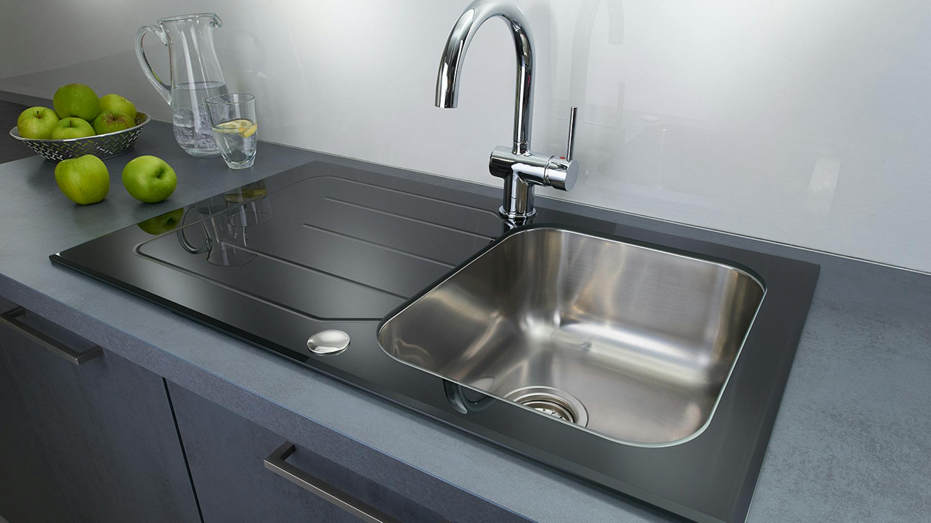 Grau-schwarze Küchenspüle mit Äpfeln und Glaskaraffe