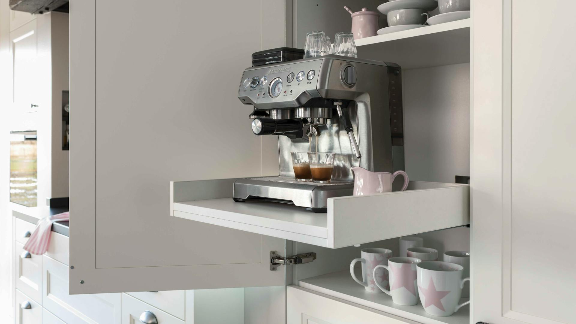 Eine Espressomaschine steht in einem Küchenschrank.