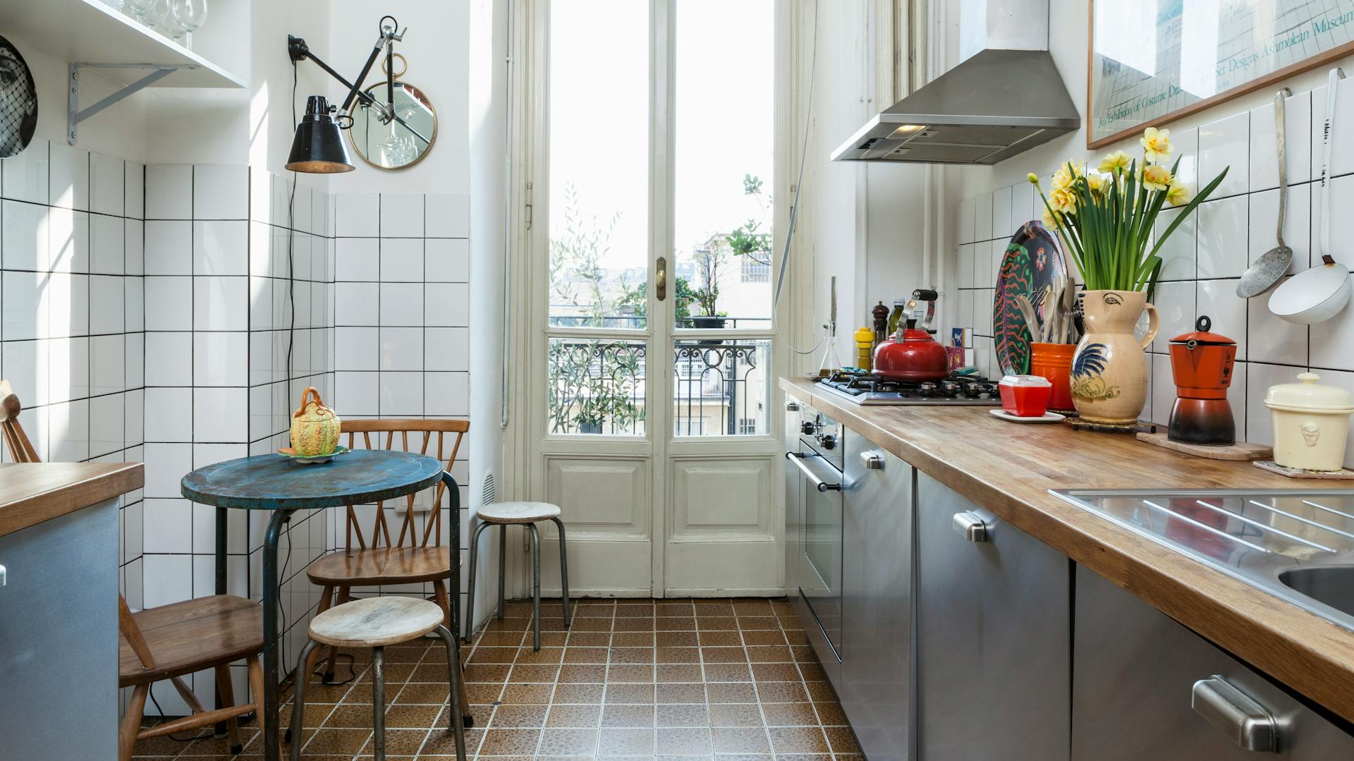 Neben einer Küchenzeile steht ein kleiner Tisch mit Stühlen.