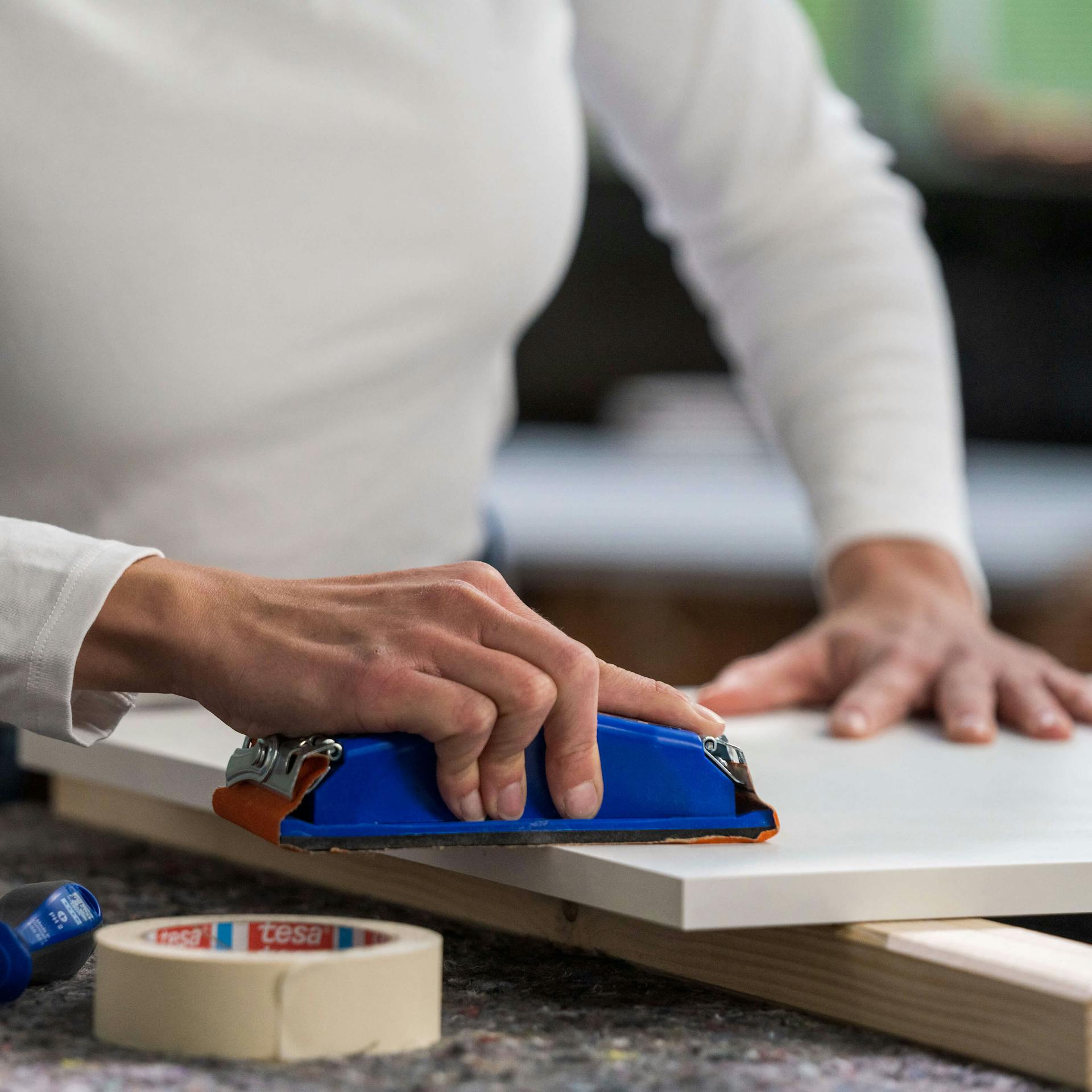 Egy konyhaszekrény frontjának csiszolása finom csiszolópapírral.