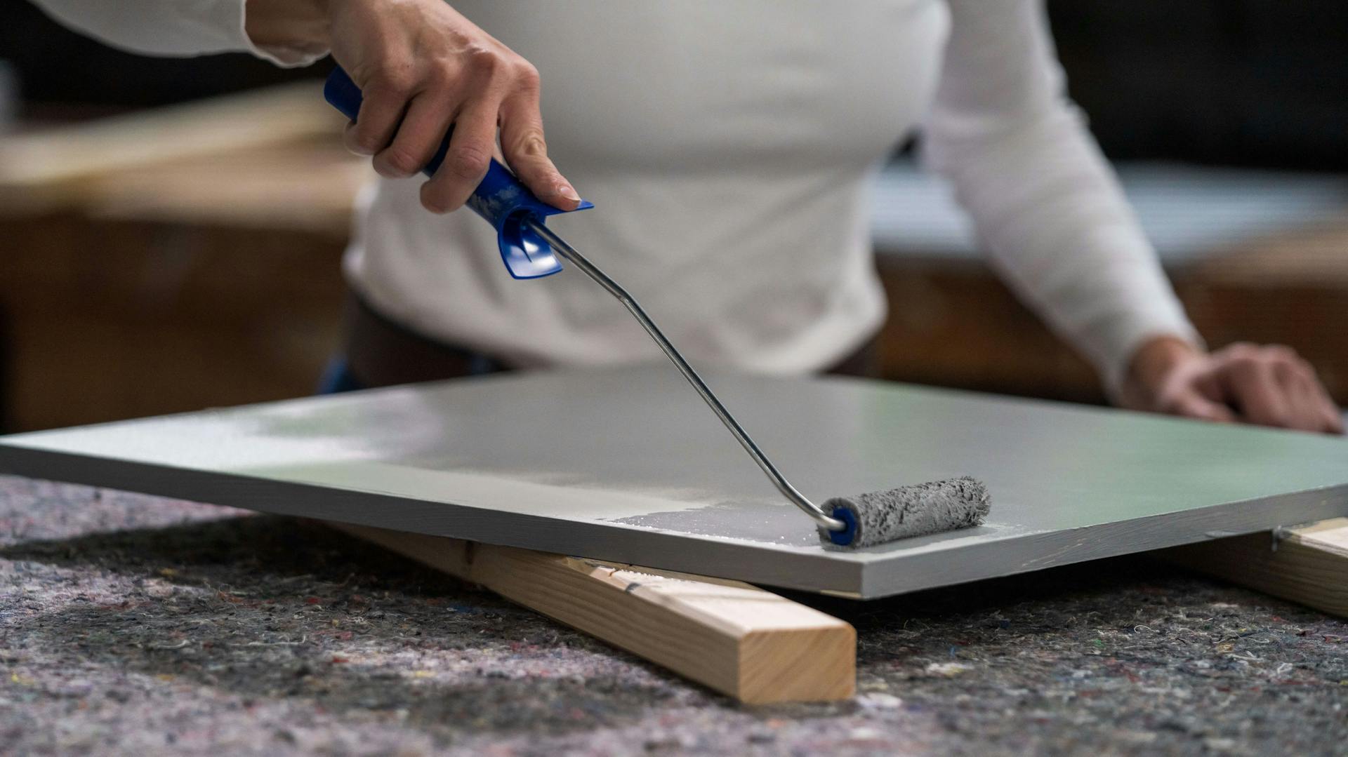 Person streicht eine Küchenfront mit einem Farbroller