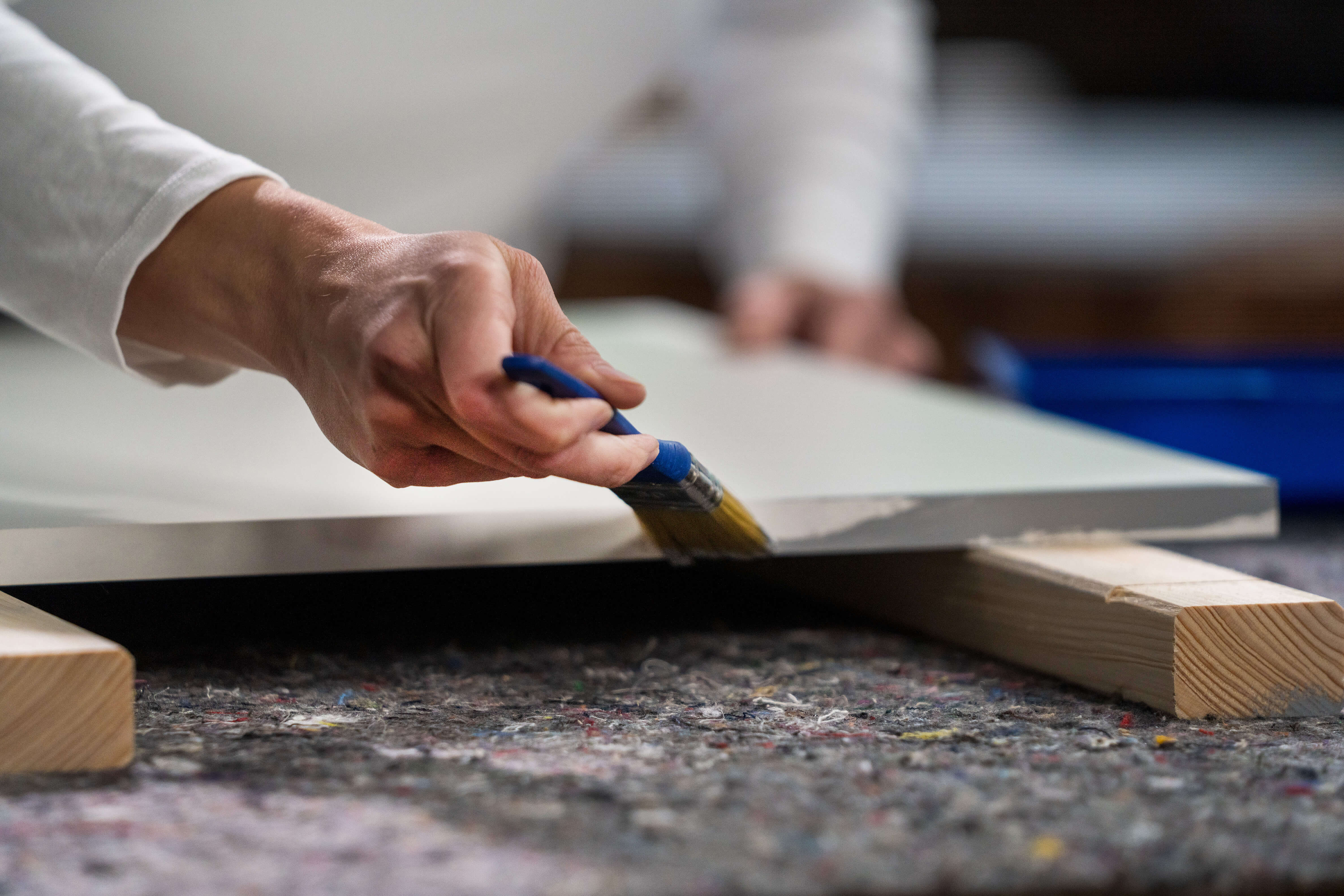 Egy konyhai front oldalainak lakkozása szürke festékkel.