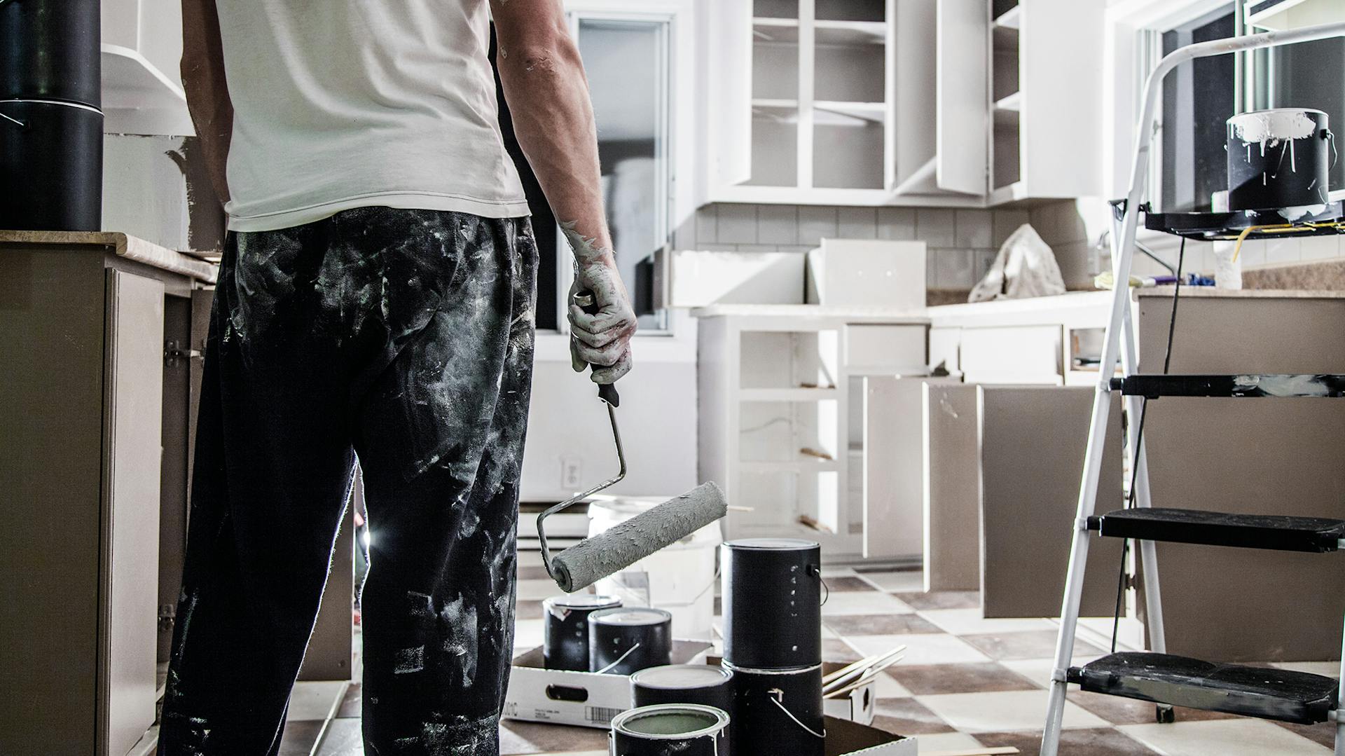 Jemand streicht Küchenmöbel oder Küchenschränke weiß.