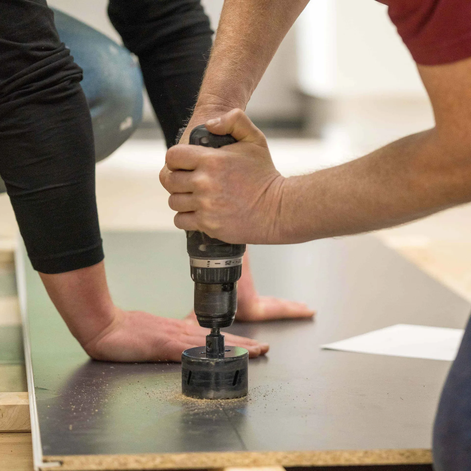 Zwei Handwerker schneiden Aussparungen für Steckdosen in eine Küchenrückwand.