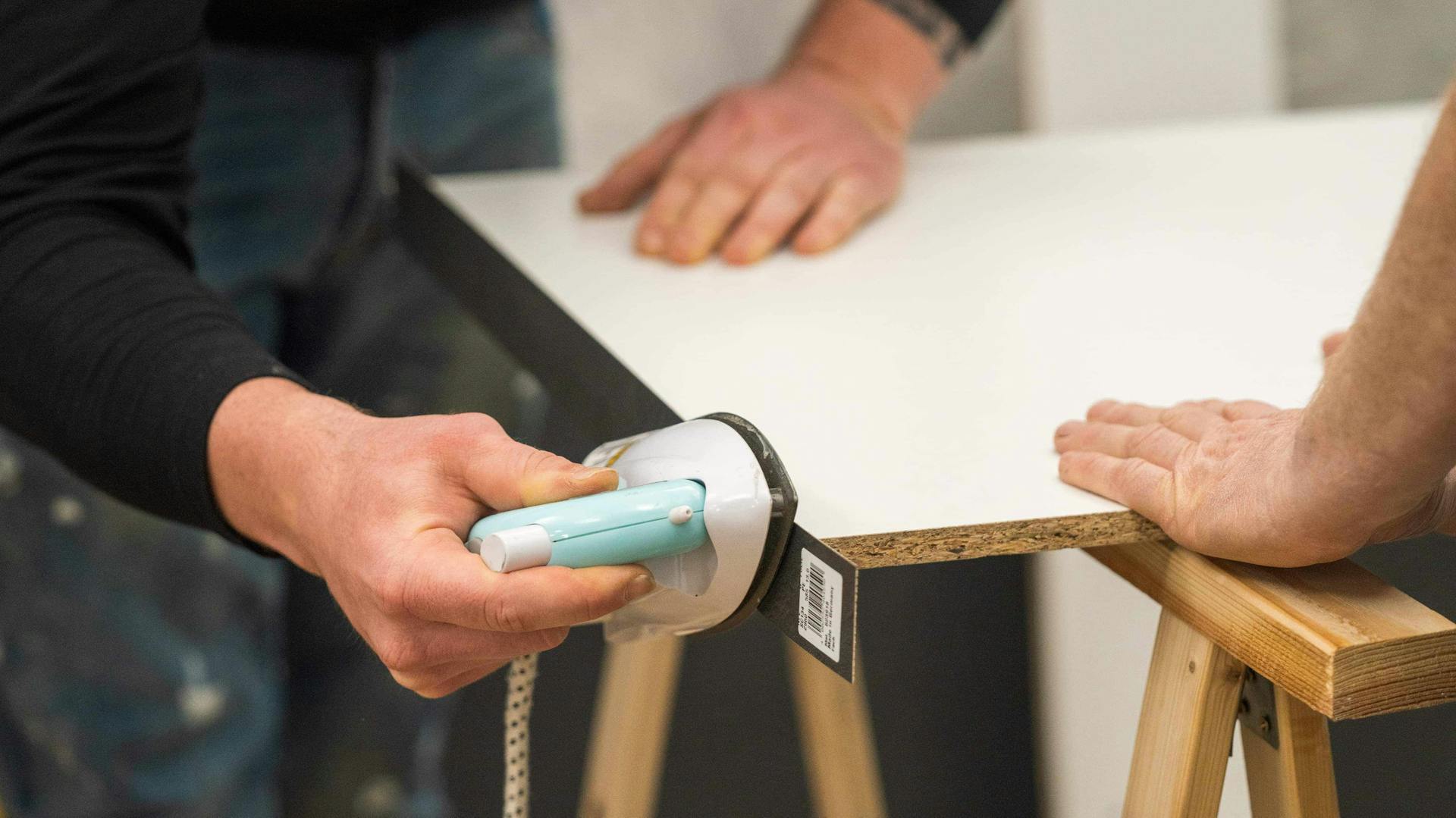 Jemand erwärmt den Kleber des Umleimers mit einem Bügeleisen.