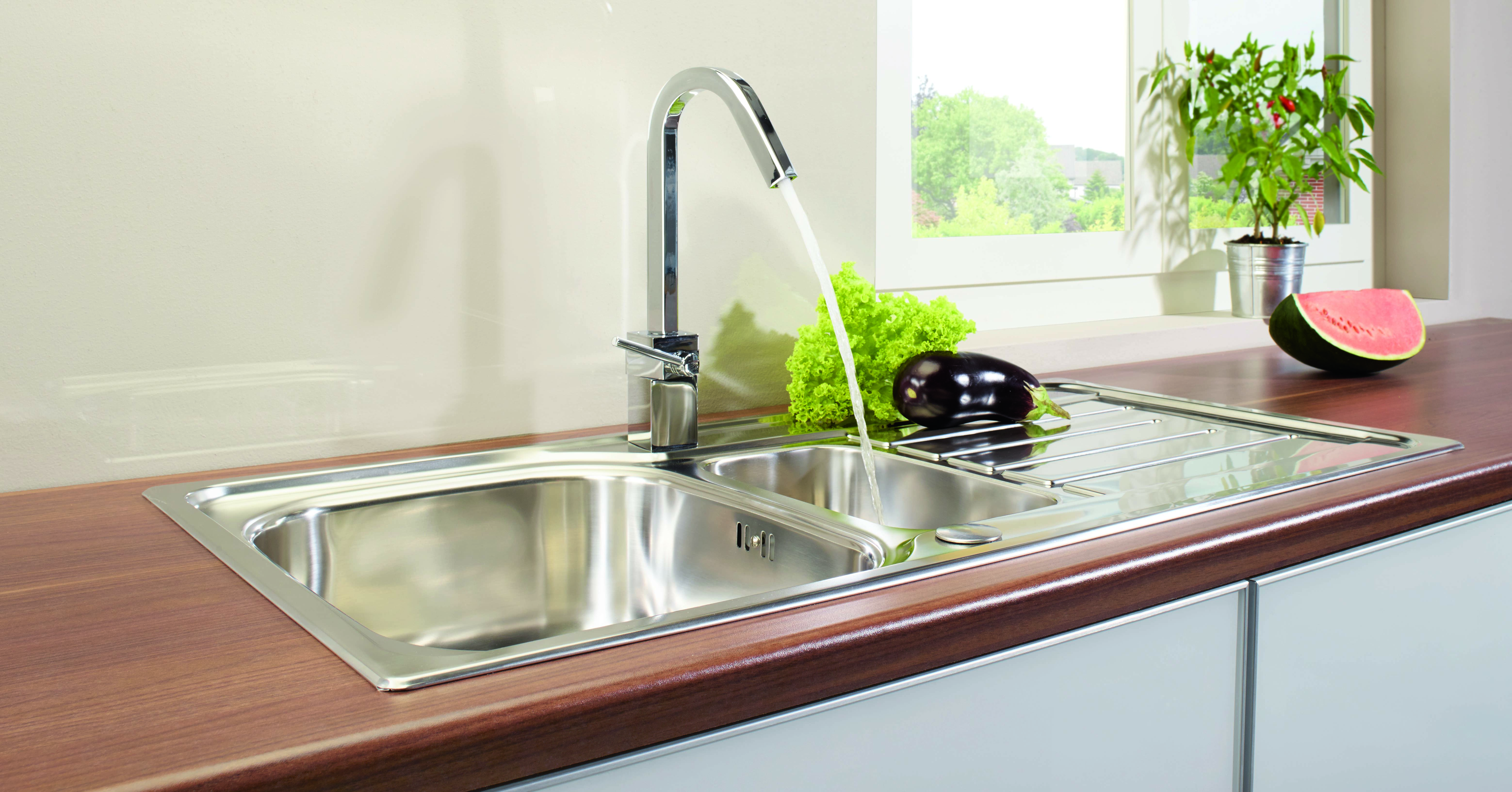 Fertige Küche mit Spüle und laufendem Wasserhahn in der Arbeitsplatte