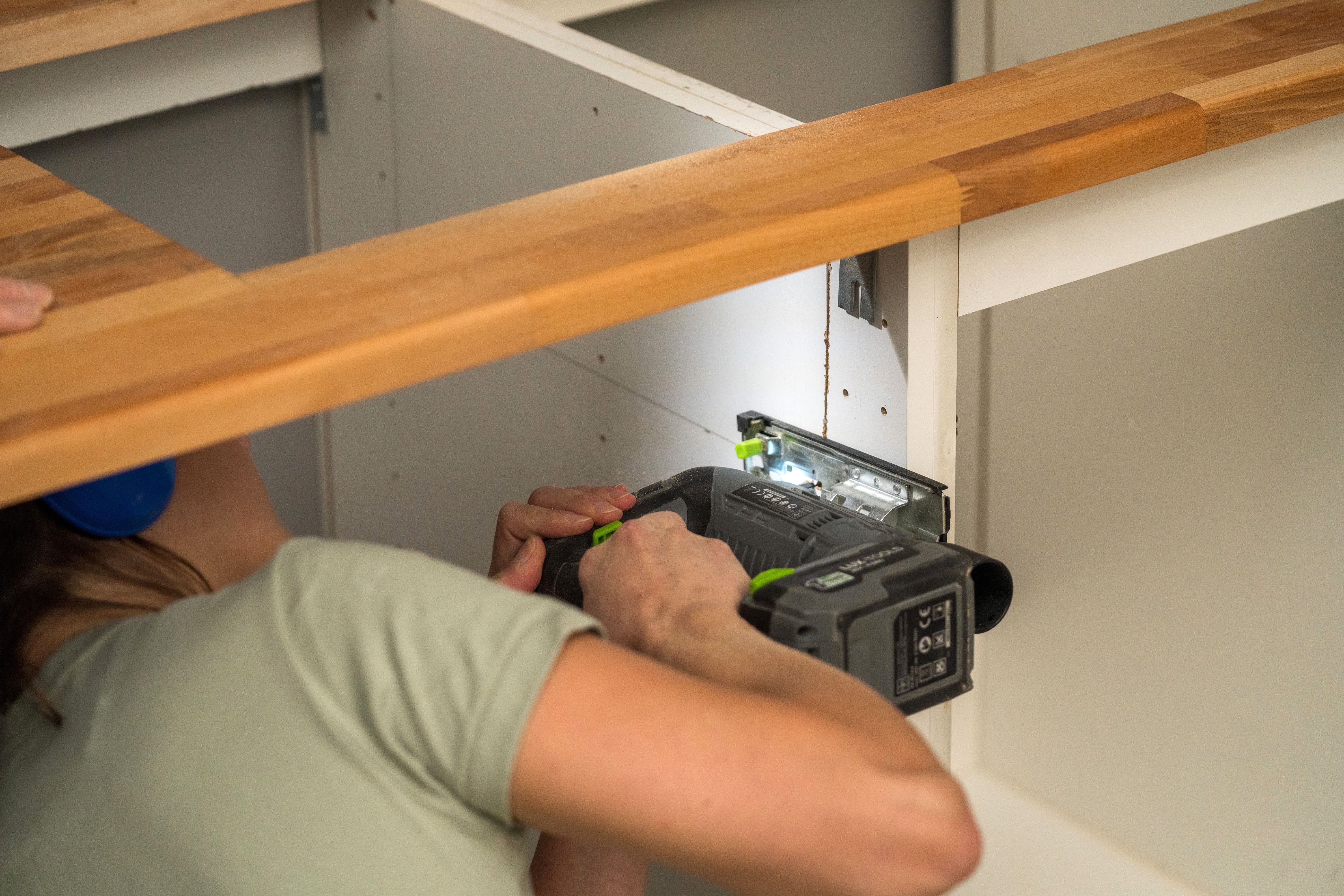 Heimwerker sägt den Unterschrank der Spüle zu.