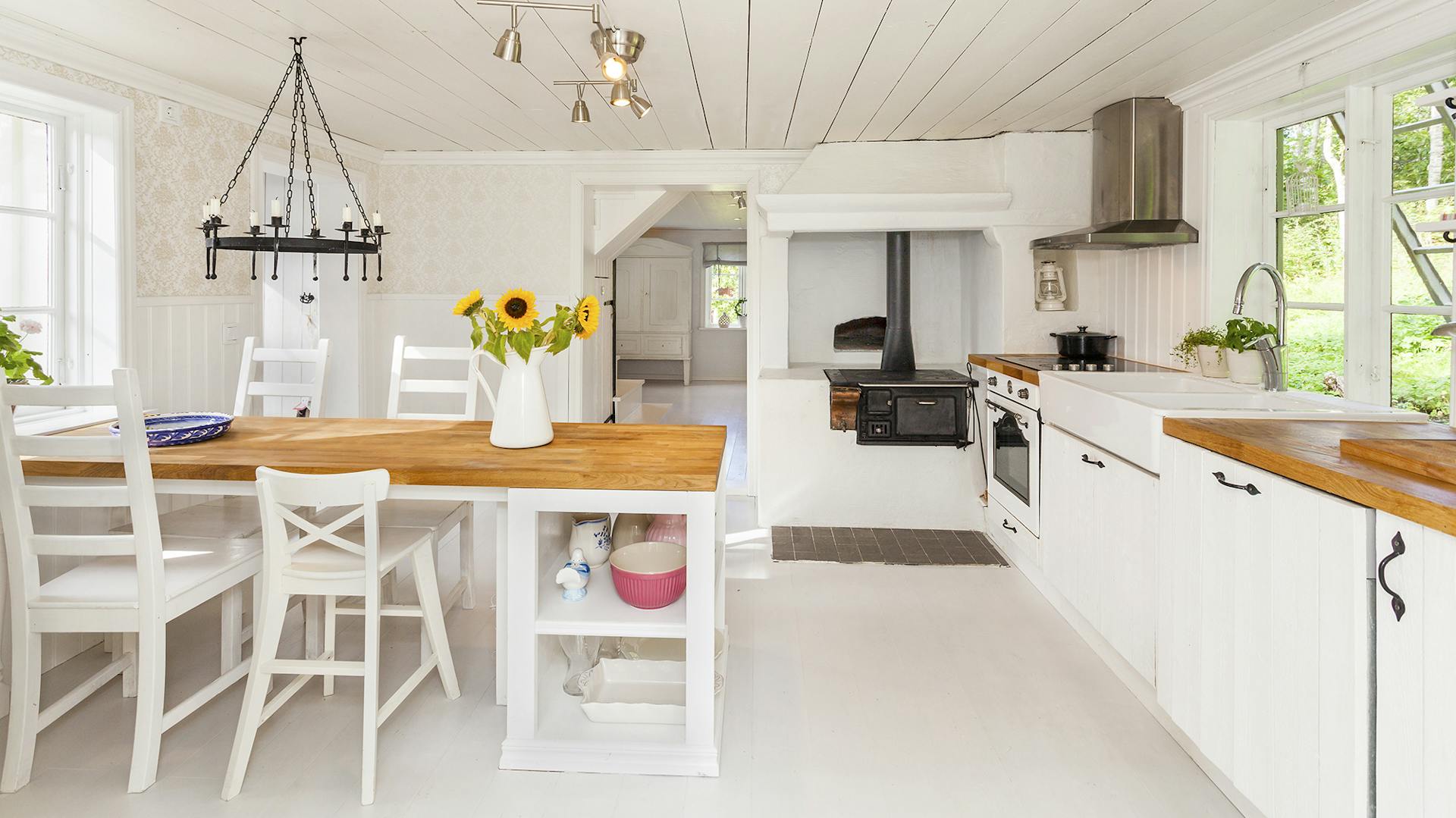 Weiße Landhausküche mit Essplatz und Holzarbeitsplatte