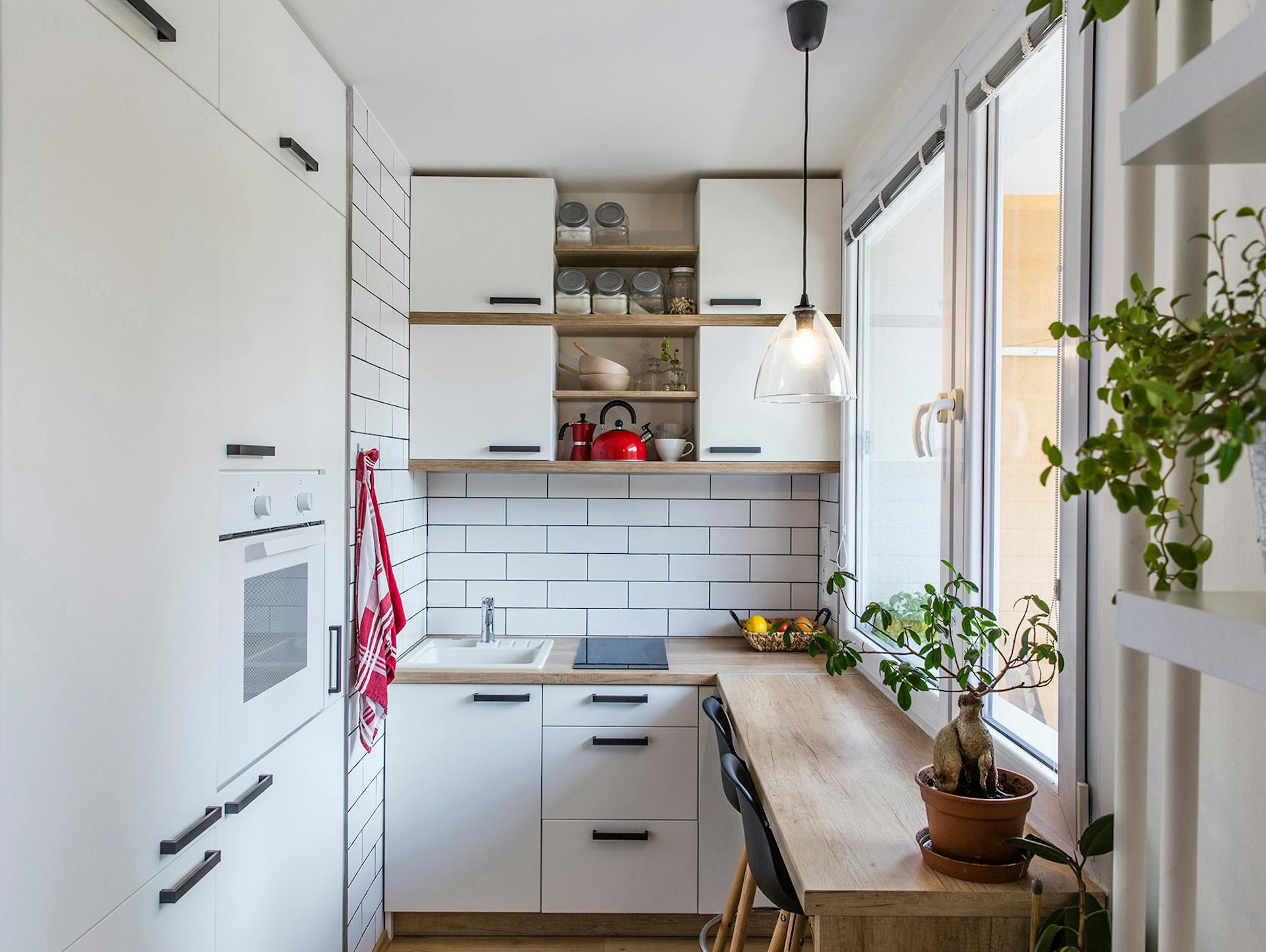 Eine kleine Küche in L-Form mit Geräten und Gegenständen ist zu sehen.