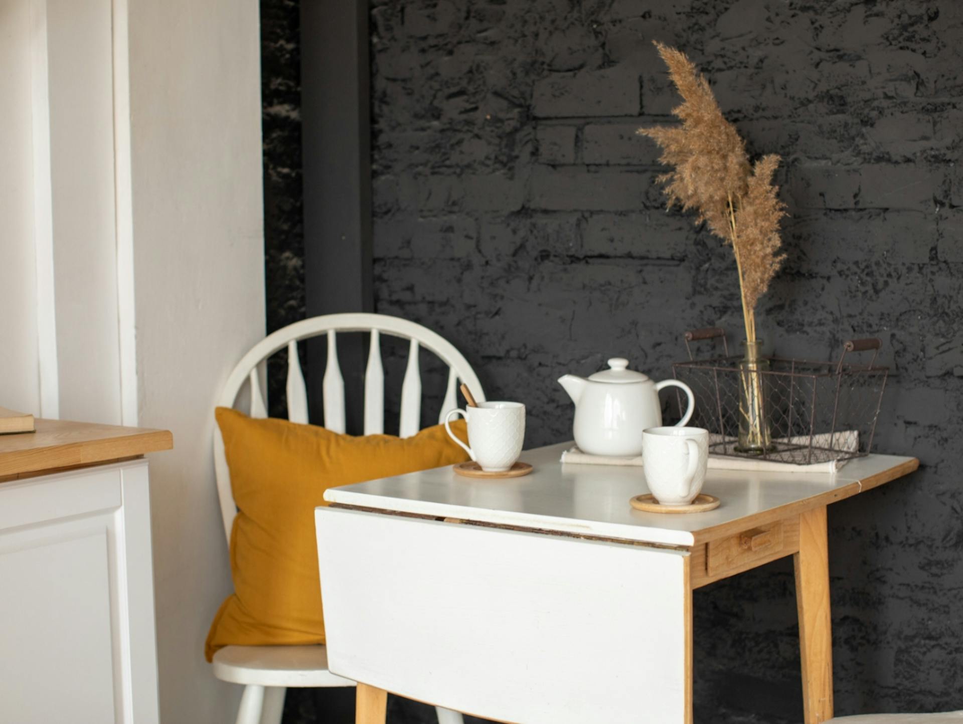 Weißer Klapptisch vor schwarzer Wand mit Stuhl.