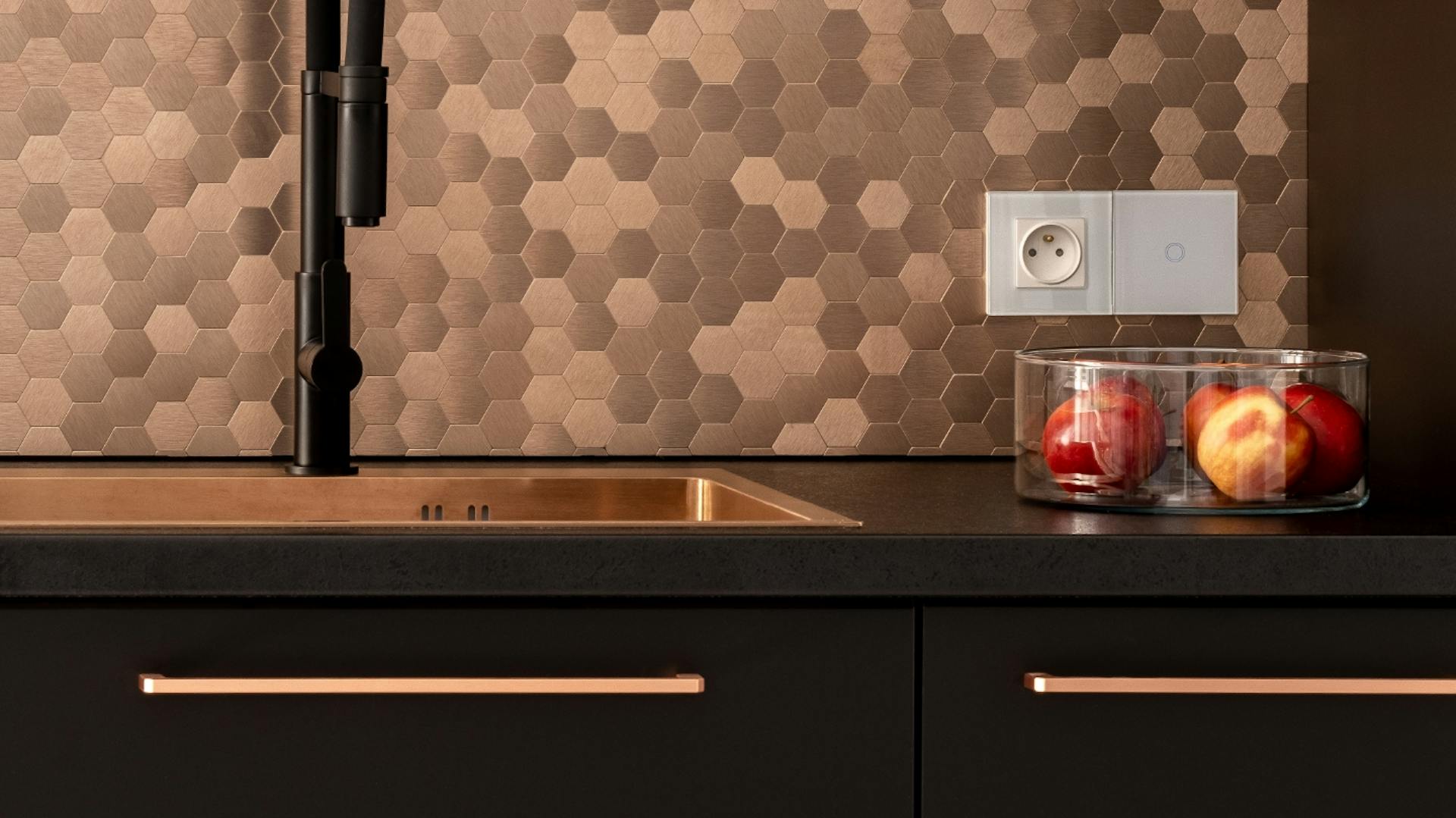 Moderne Küche in mattschwarz mit bronzefarbenen Griffen und Rückwand sowie schwarzem Wasserhahn.