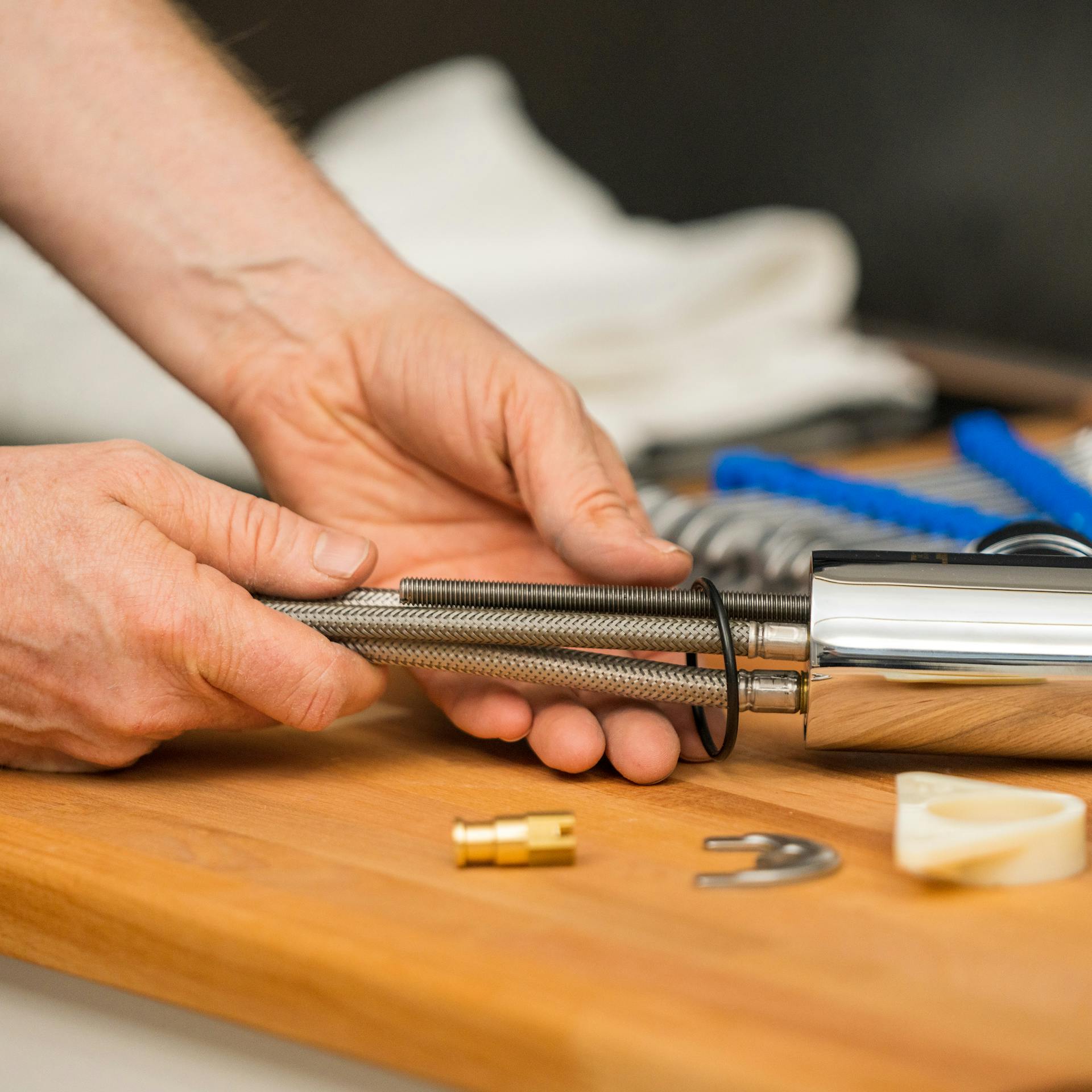 Egy barkácsoló áthúzza az O-gyűrűt a csaptelep tömlőin.