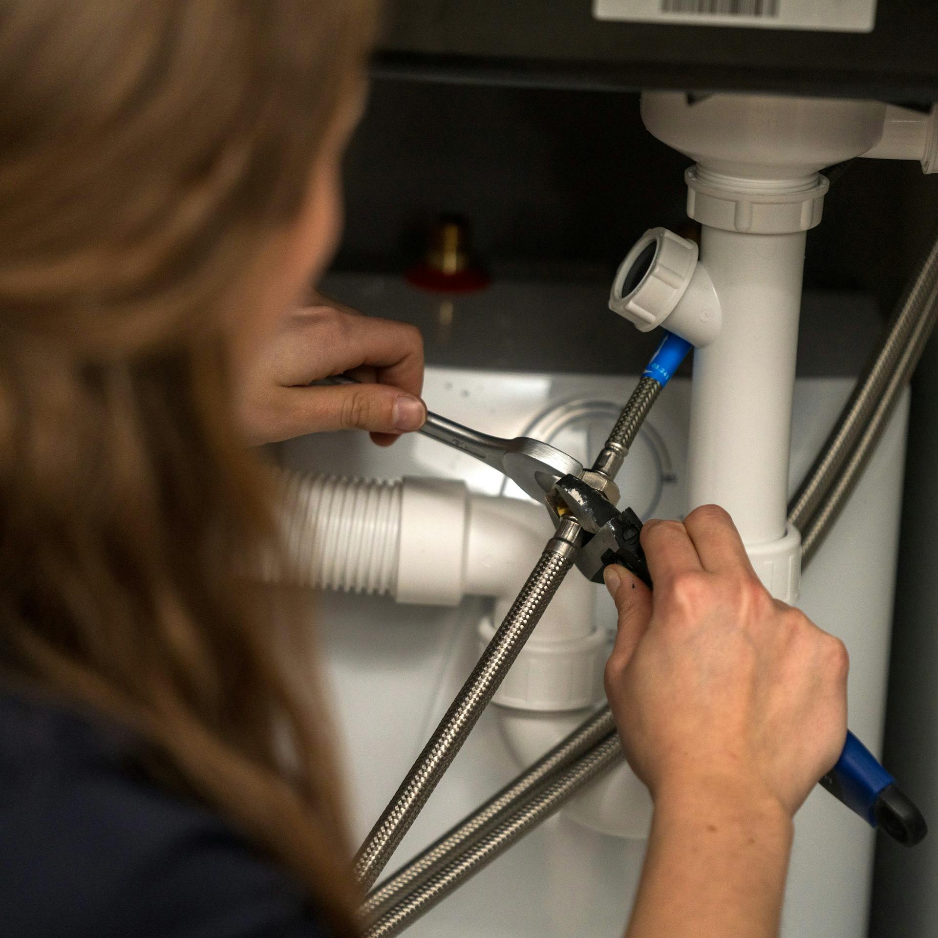 Egy barkácsoló nő rögzíti a hosszabbító csövet.