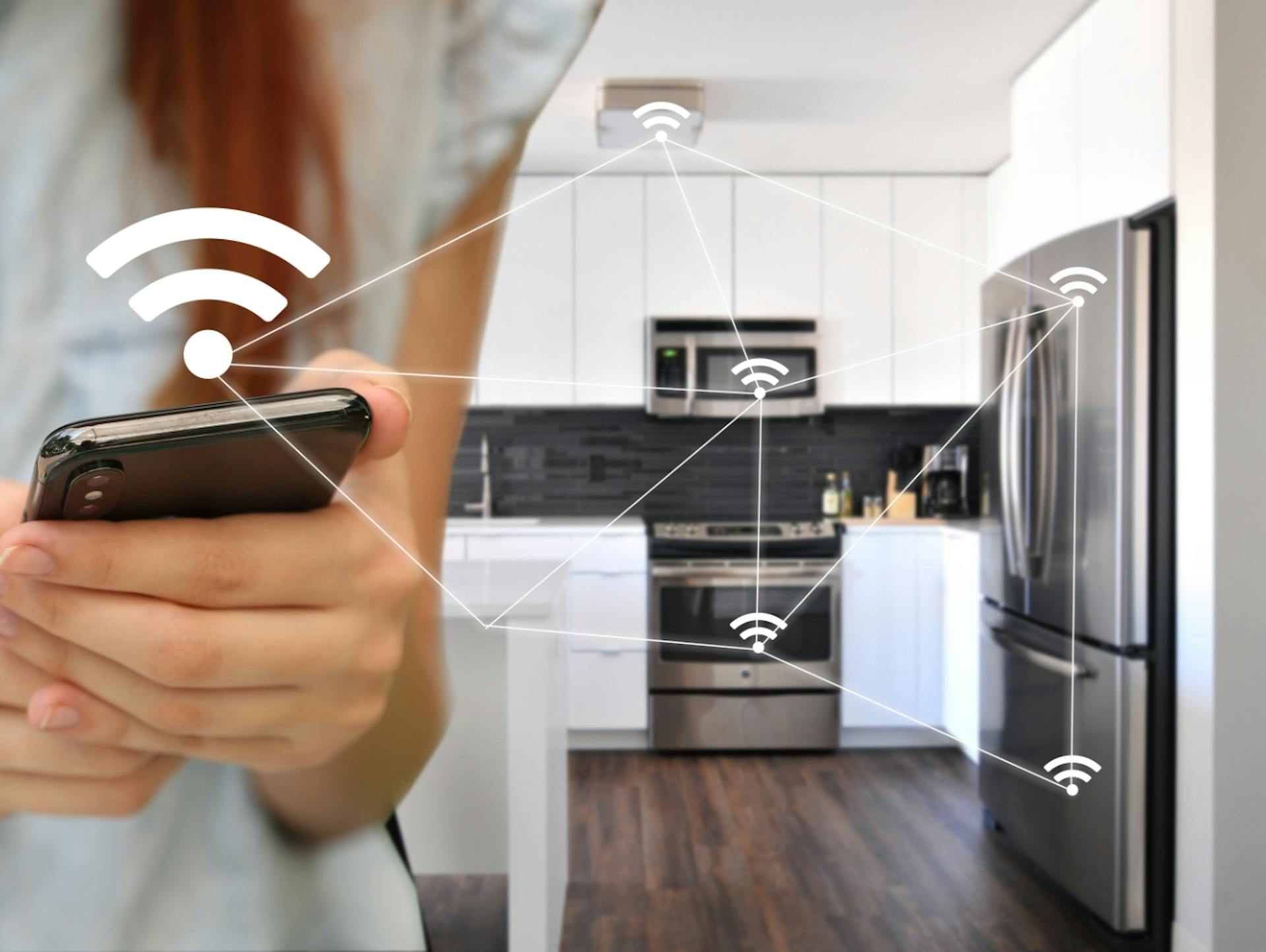 Person steuert Elektrogeräte in der Küche per App.