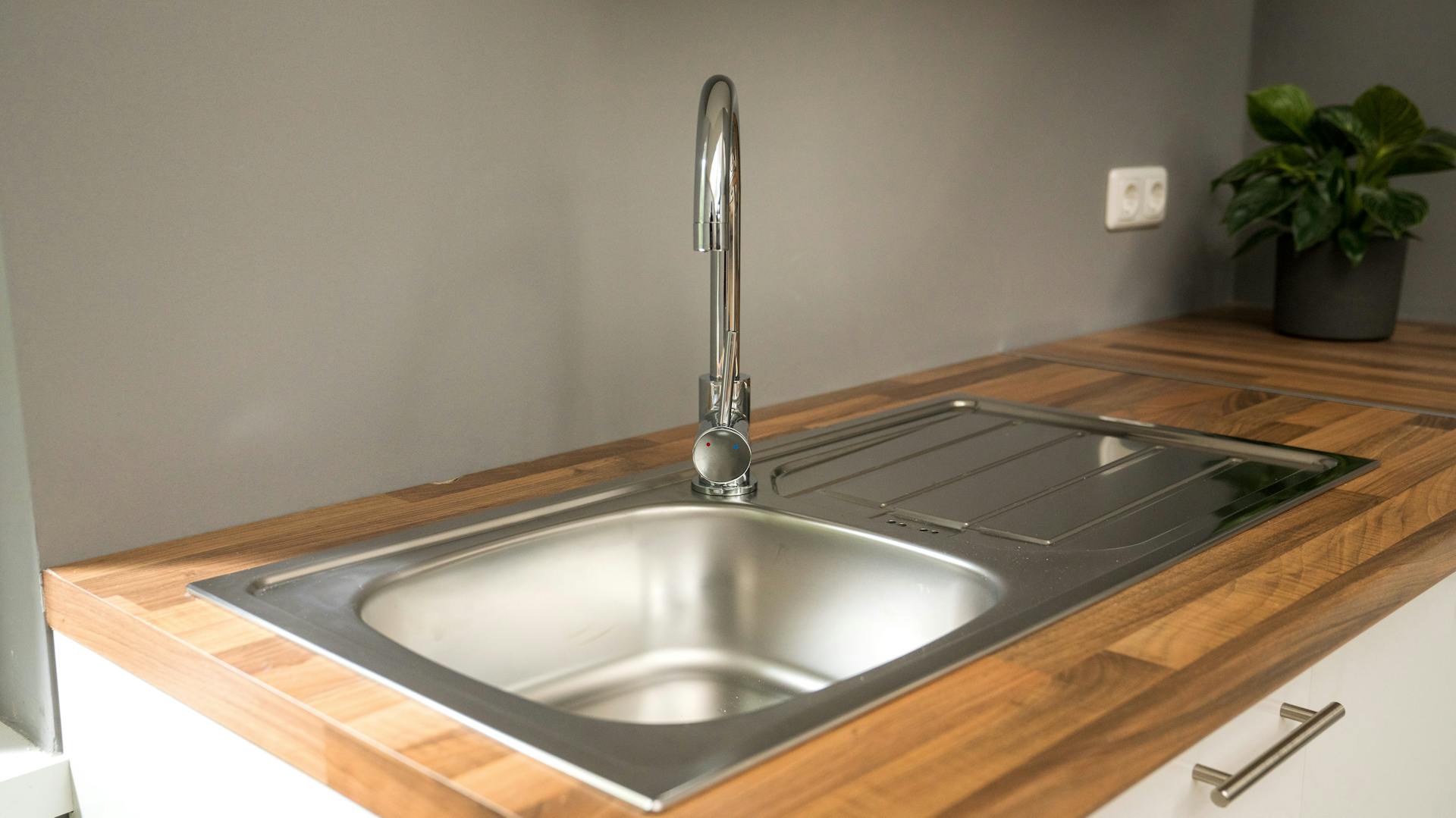 Neue Spüleinheit in heller Küche mit brauner Arbeitsplatte.