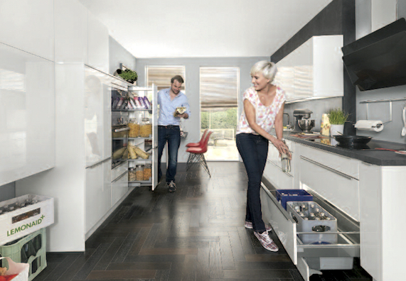 Paar räume Lebensmittel in Küchenschränke und Kühlschrank in weißer Küche ein.